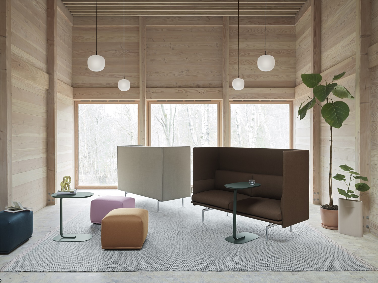 Innenaufnahme mit Muuto Echo Pouf Hockern in verschiedenen Farben und einem braunen Sofa mit hoher Rückenlehne.