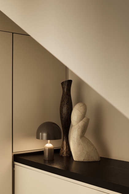 Silberne Tom Dixon Bell Portable LED Akkuleuchte auf einem Regal mit Dekoration.