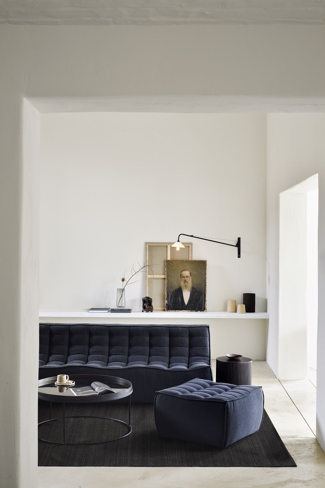 Ethnicraft Couchtisch Tabletttisch in modernem Wohnzimmer mit Sofa, Hocker und Teppich in dunklen Farben.