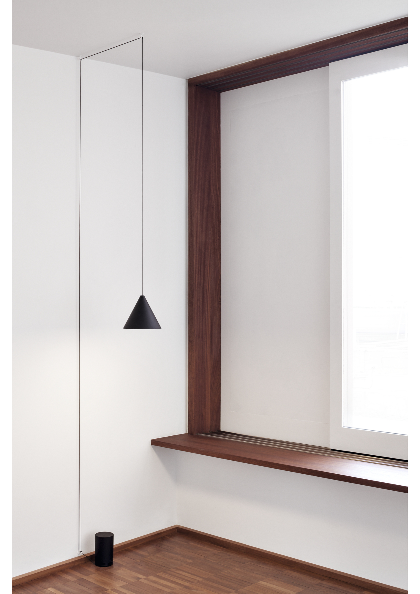 Schwarze String Light Cone Pendelleuchte von Flos in minimalistischem Raum mit Holzdetails und Fenster.