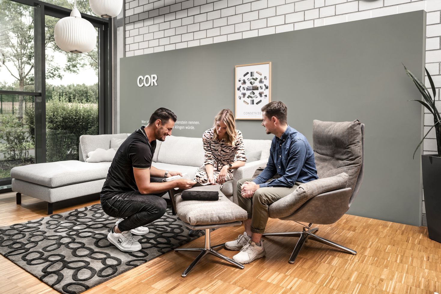 Drei Personen sitzen in einem modern eingerichteten Raum mit COR Möbeln, Sofa und Sessel.