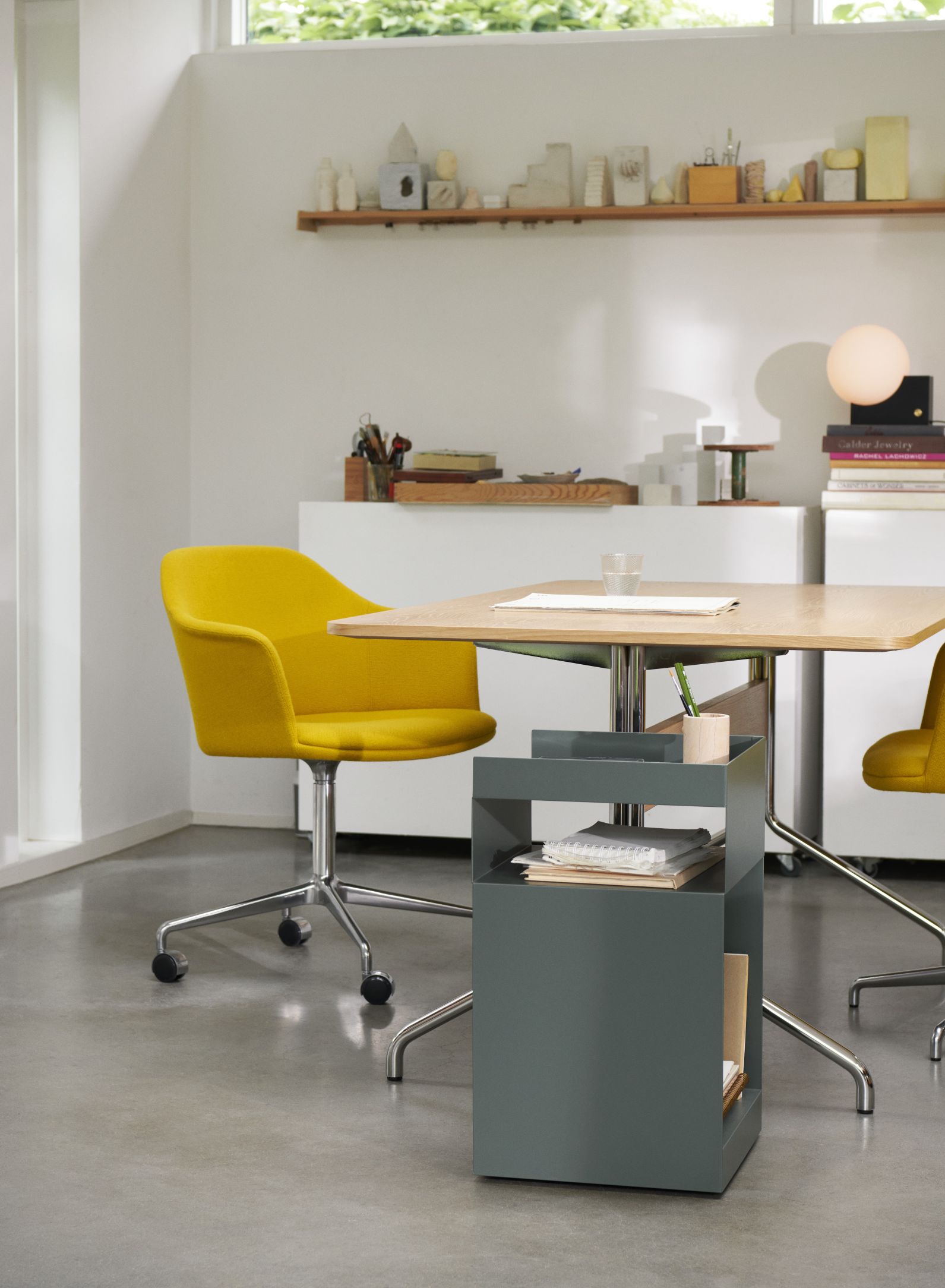Pavilion AV18 Tisch von AndTradition mit gelbem Bürostuhl und grauem Rollcontainer in modernem Büro.