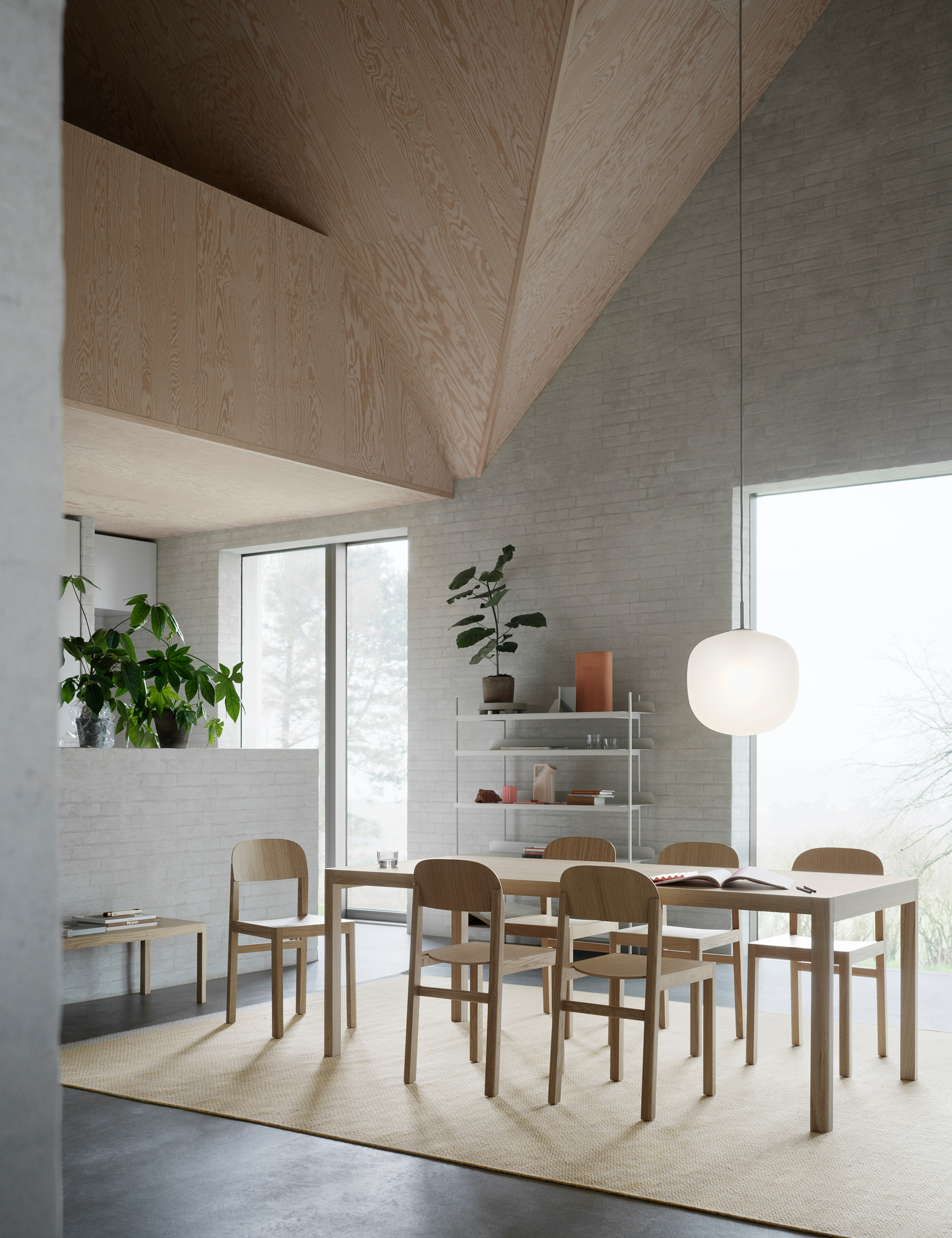 Heller Raum mit Muuto Workshop Table Esstisch und Stühlen aus hellem Holz auf beigem Teppich.