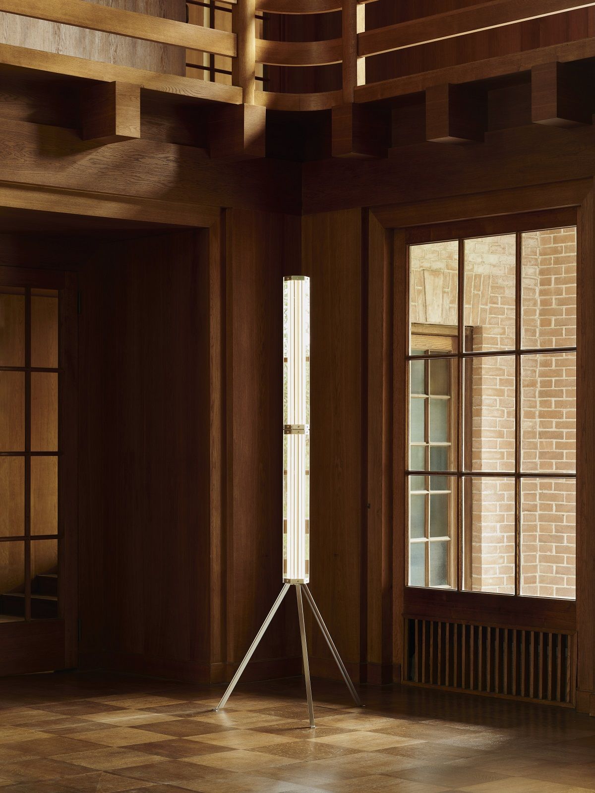 Superwire F Stehleuchte von Flos: Moderne Stehlampe mit Tripod-Fuß in holzvertäfeltem Raum.