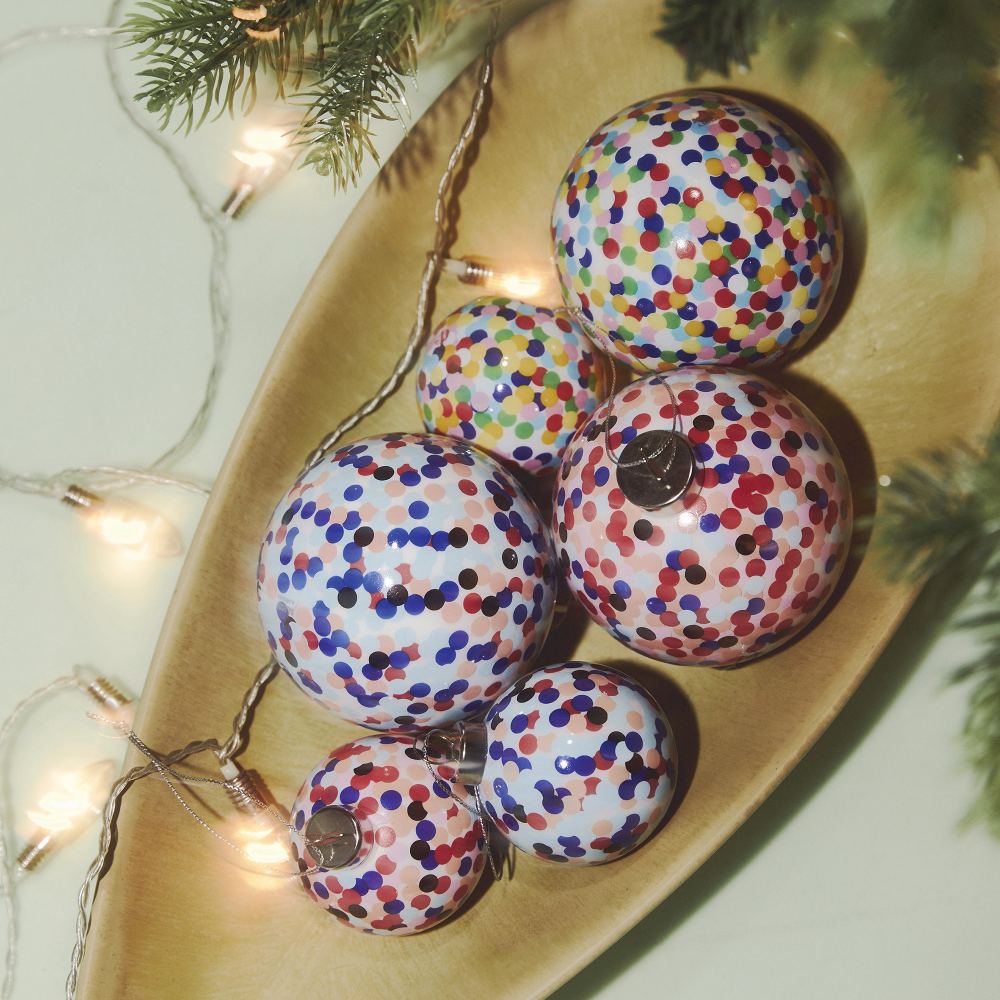 Alessi Proust Weihnachtskugeln in Holzschale mit Lichterkette und Tannenzweigen, festliche Dekoration.