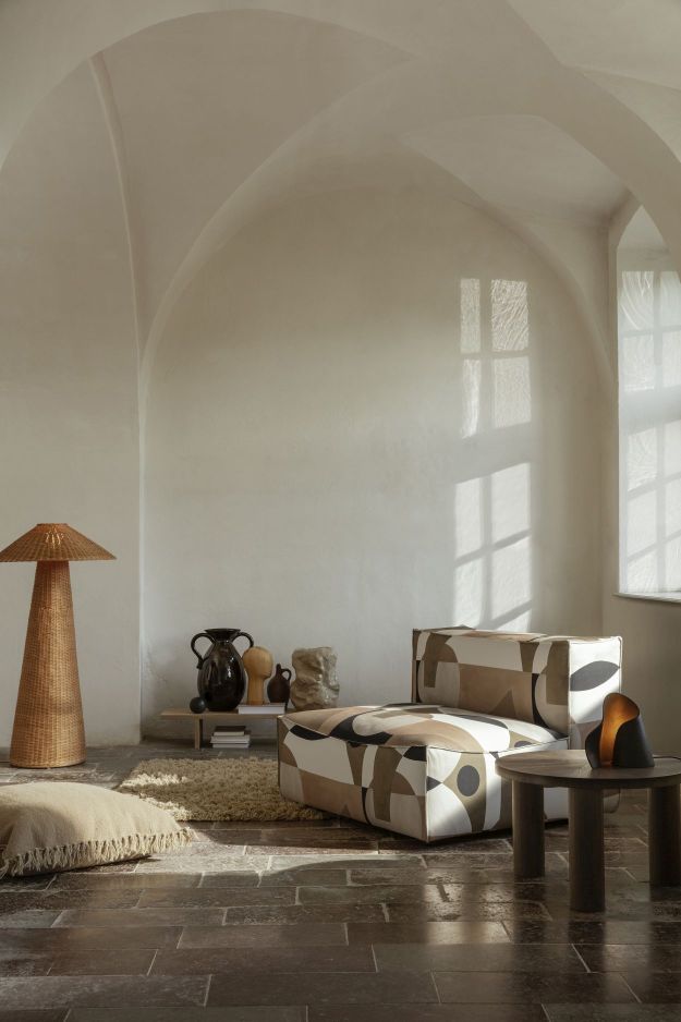 Wohnzimmer mit Ferm Living Dou Stehleuchte aus Rattan, Sessel und Dekoration.