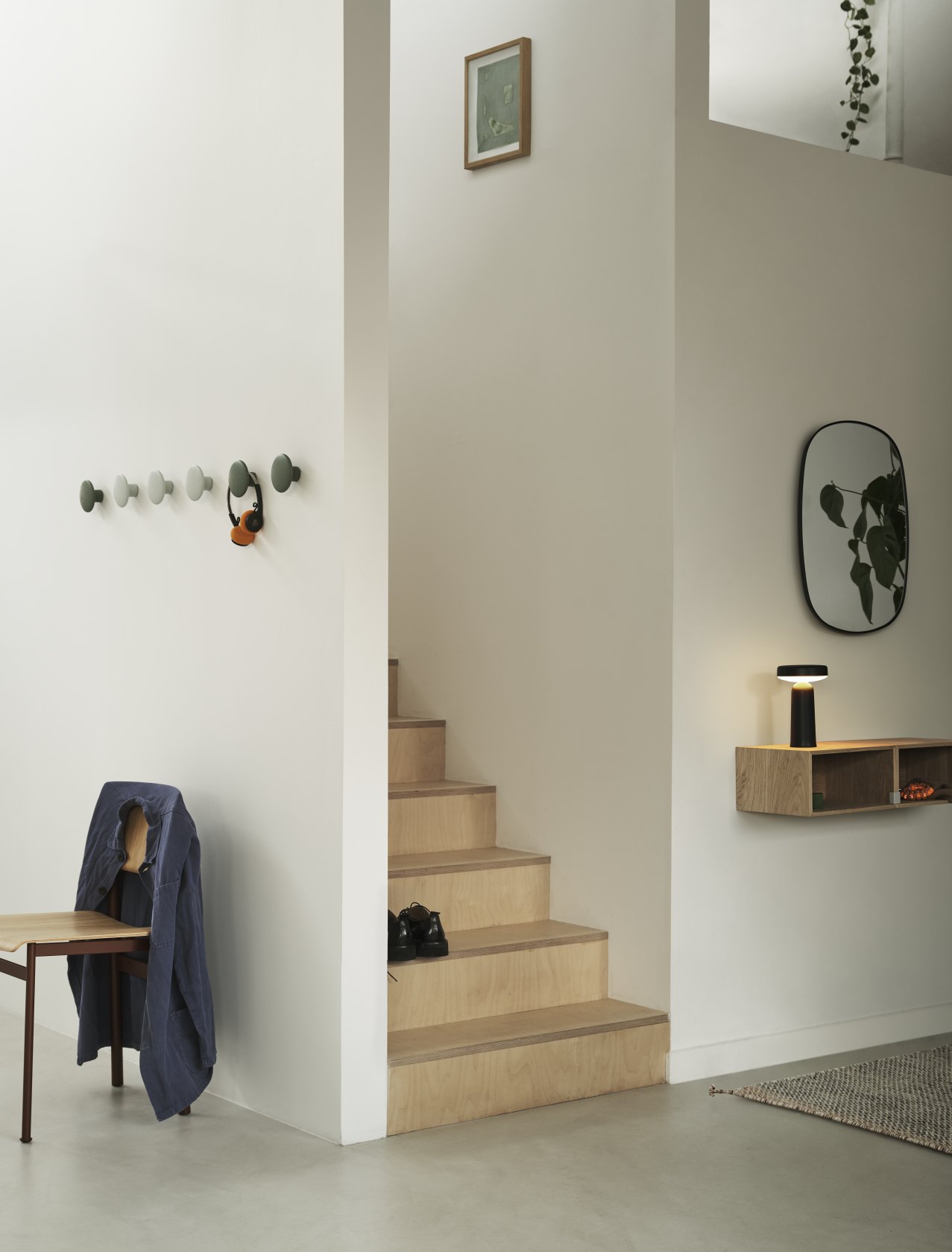 Heller Flur mit Treppe, Muuto Stacked Storage System 2.0 Regal, Lampe, Spiegel und Garderobe.