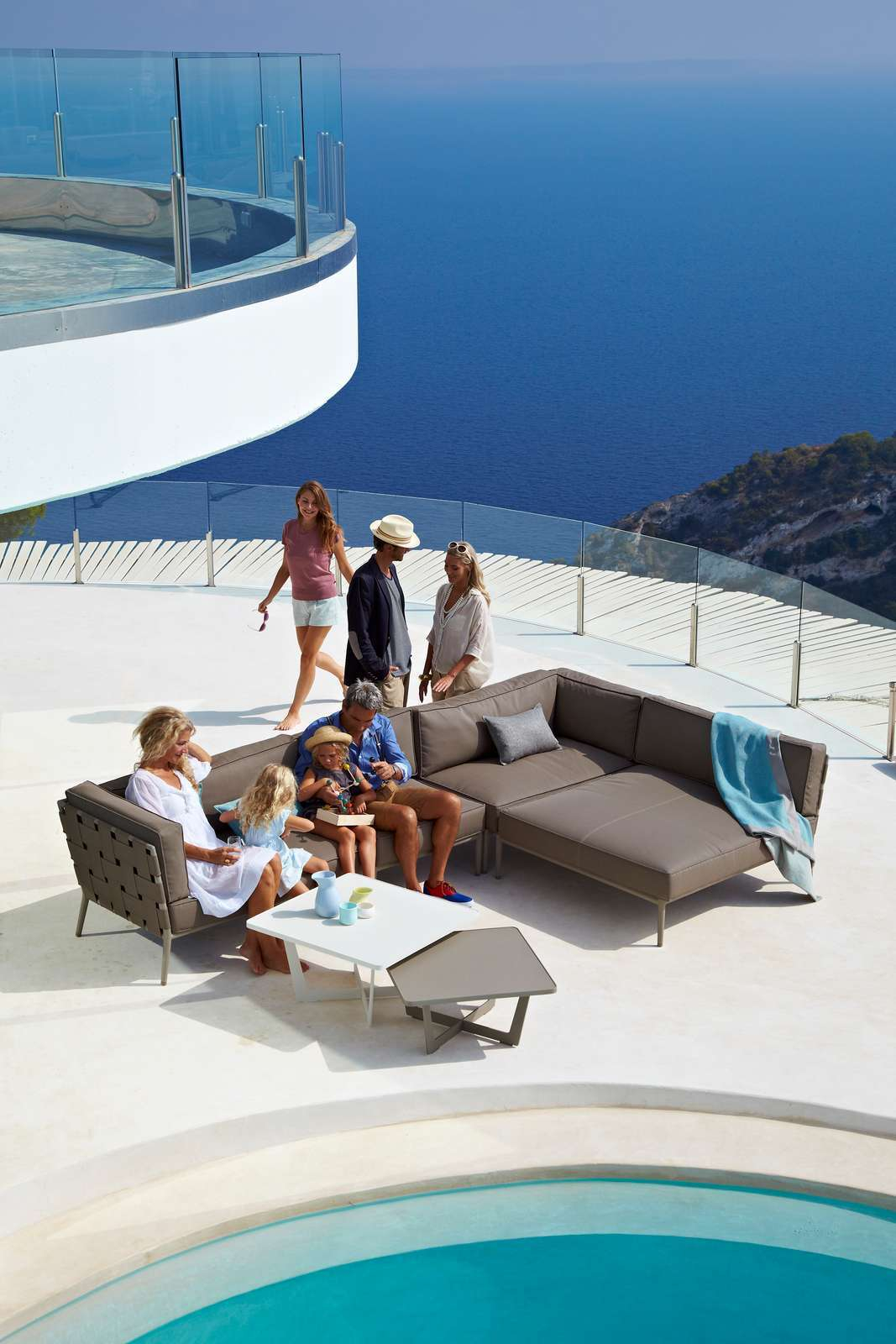 Familie entspannt auf Cane-Line Conic Outdoor Modulsofa mit Blick auf das Meer. Gartenmöbel und Lounge.