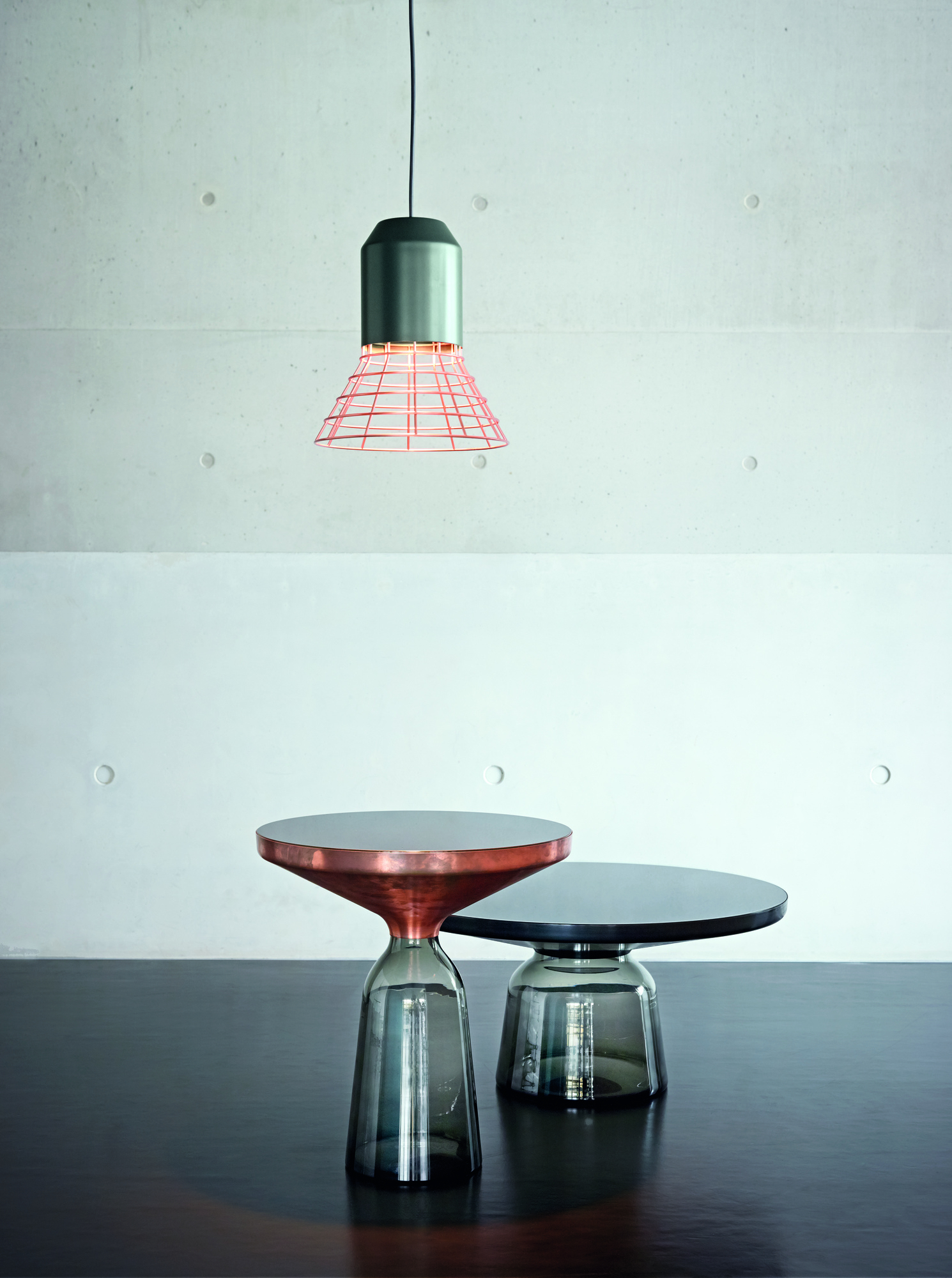 Zwei ClassiCon Bell Coffee Tables mit Marmor Tischplatten in Kupfer und Schwarz unter Lampe.