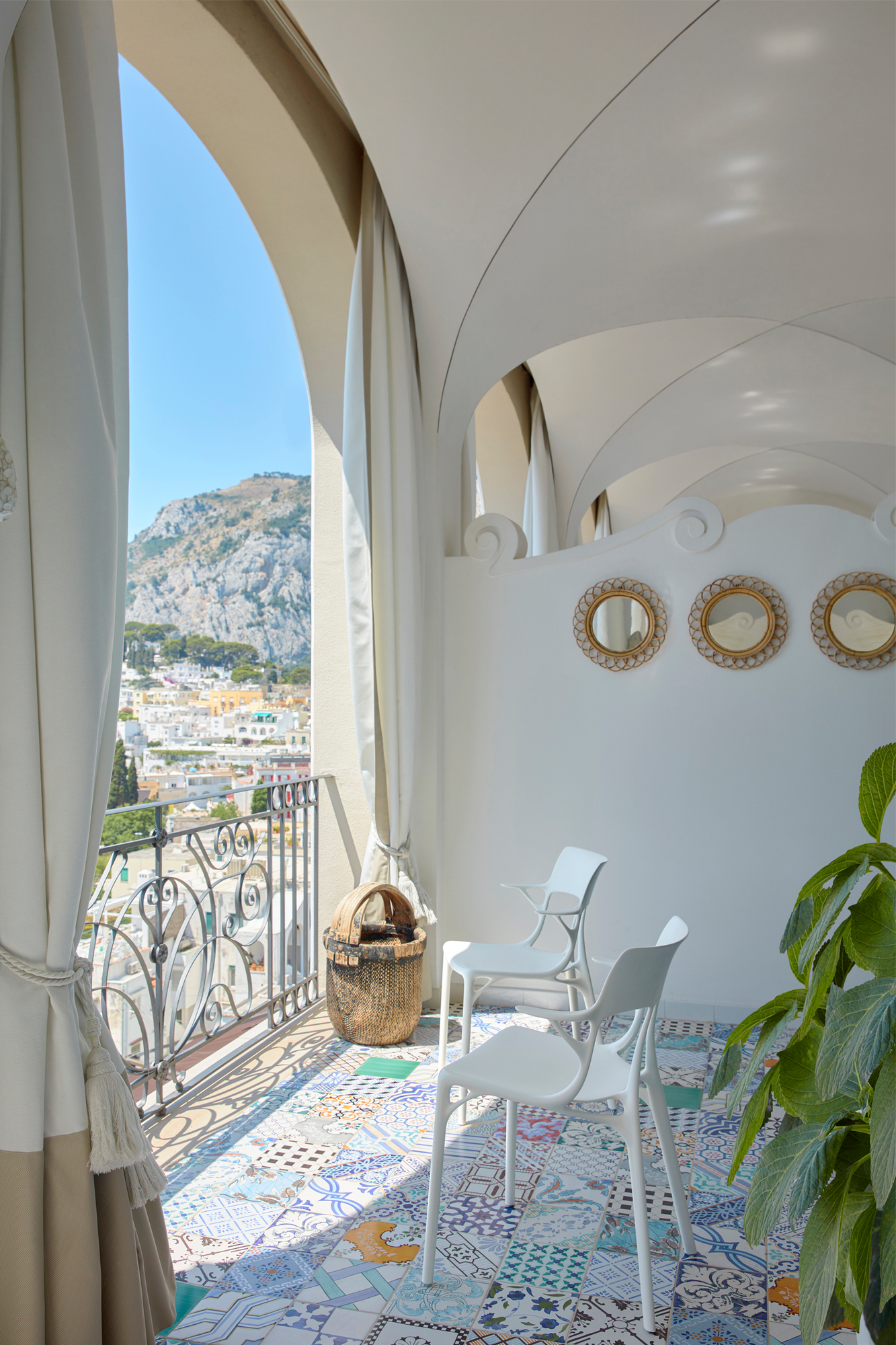Zwei weiße A.I. Stühle von Kartell auf einem Balkon mit Blick auf eine Stadt.