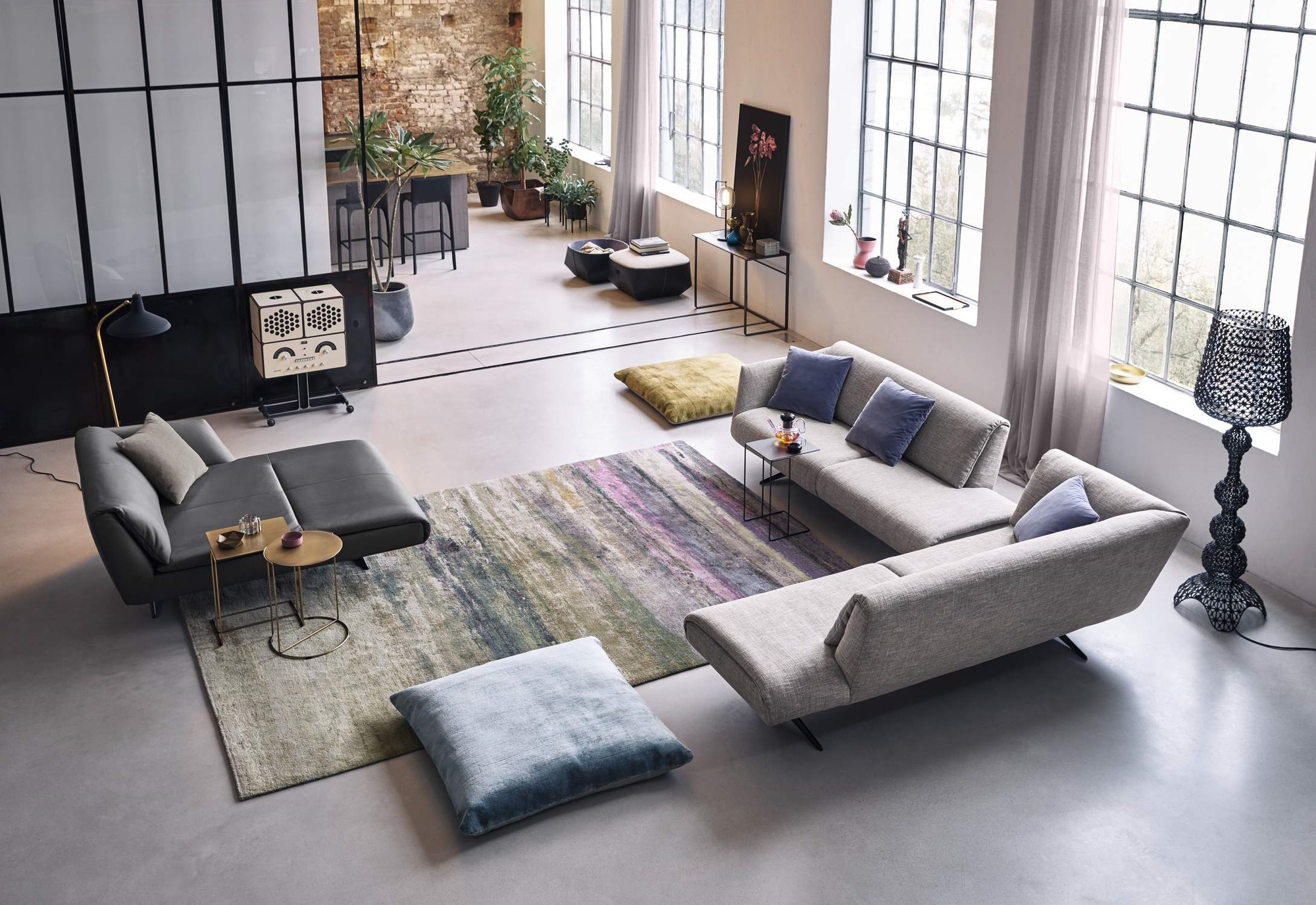 Helles Wohnzimmer mit grauer Couch, Teppich und Oki Beistelltisch von Walter Knoll mit goldenem Gestell.