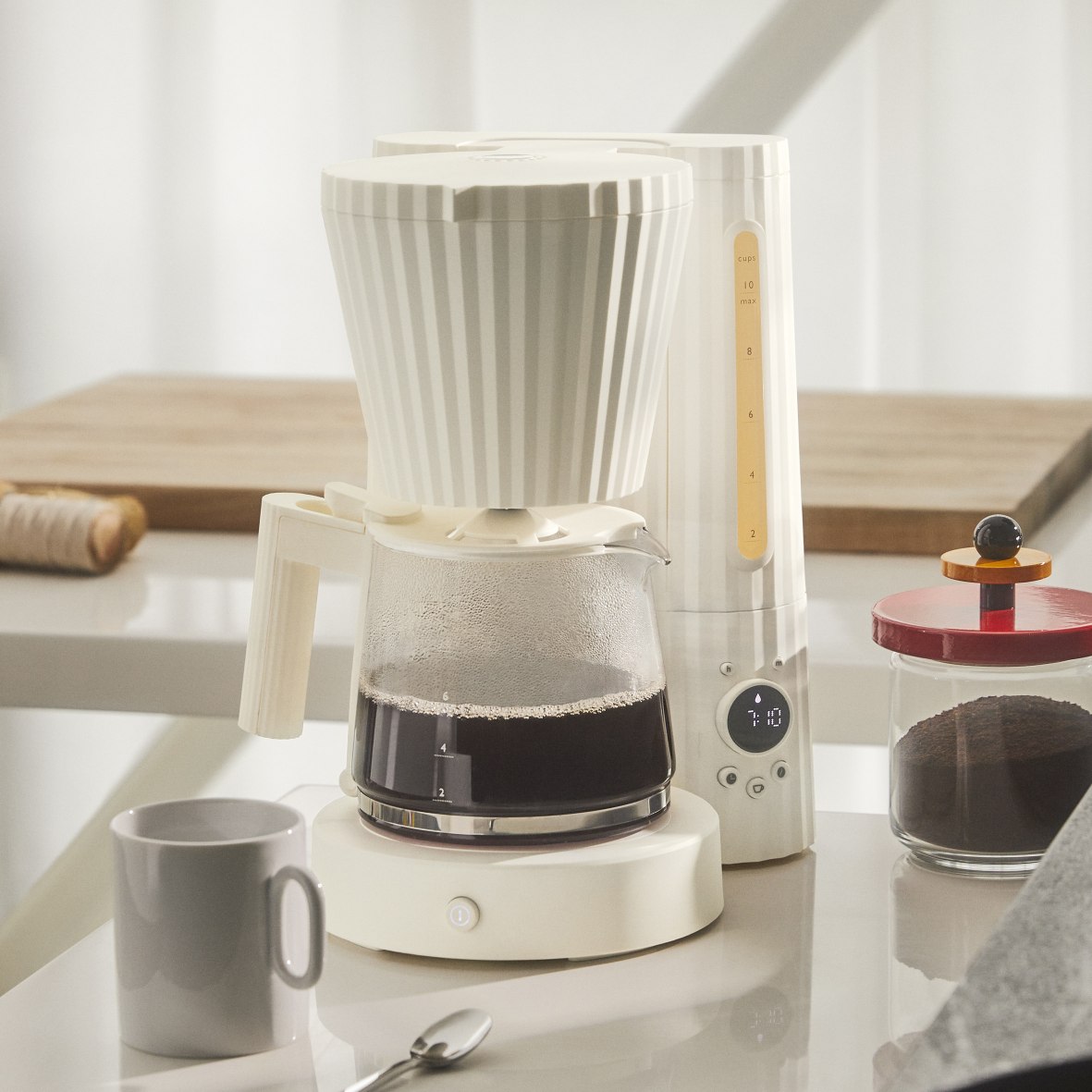 MDL14 Alessi Plissé Filterkaffeemaschine in Weiß mit Glaskanne und Tasse auf einer Küchentheke.