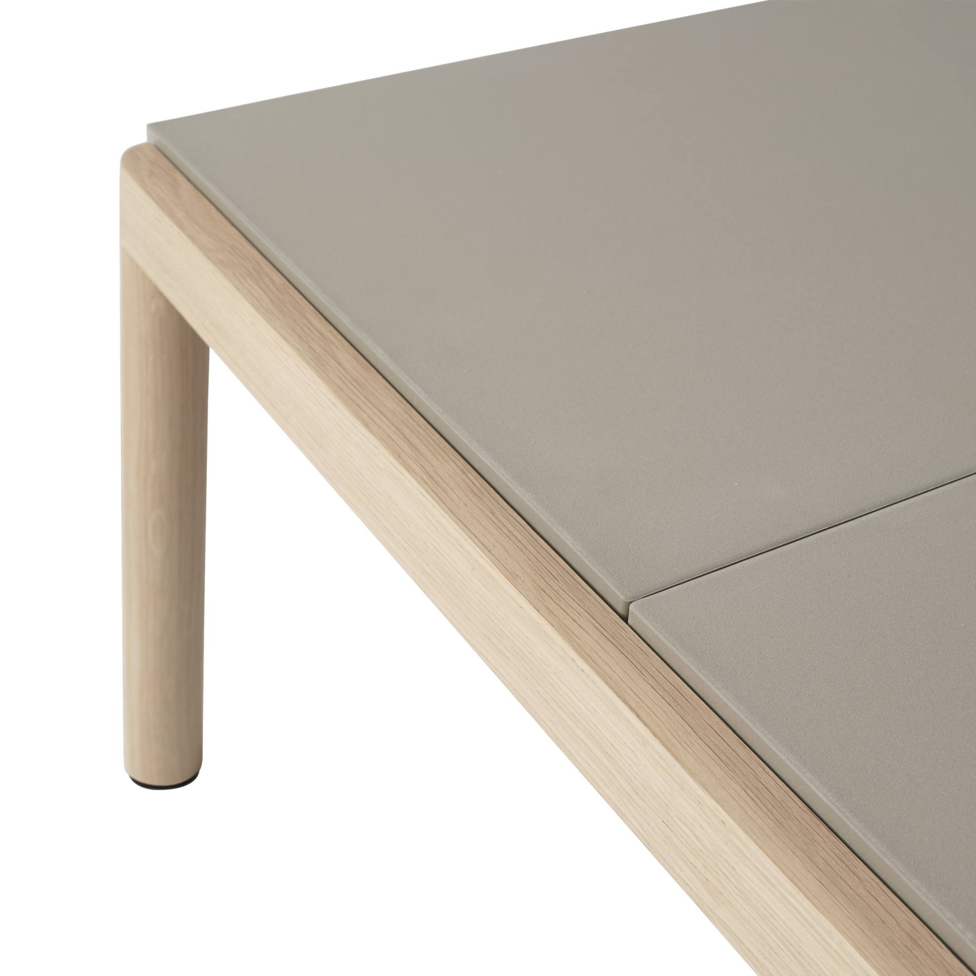 Detailaufnahme des Muuto Couple Coffee Table: Graue Tischplatte mit hellem Holzrahmen und Bein.