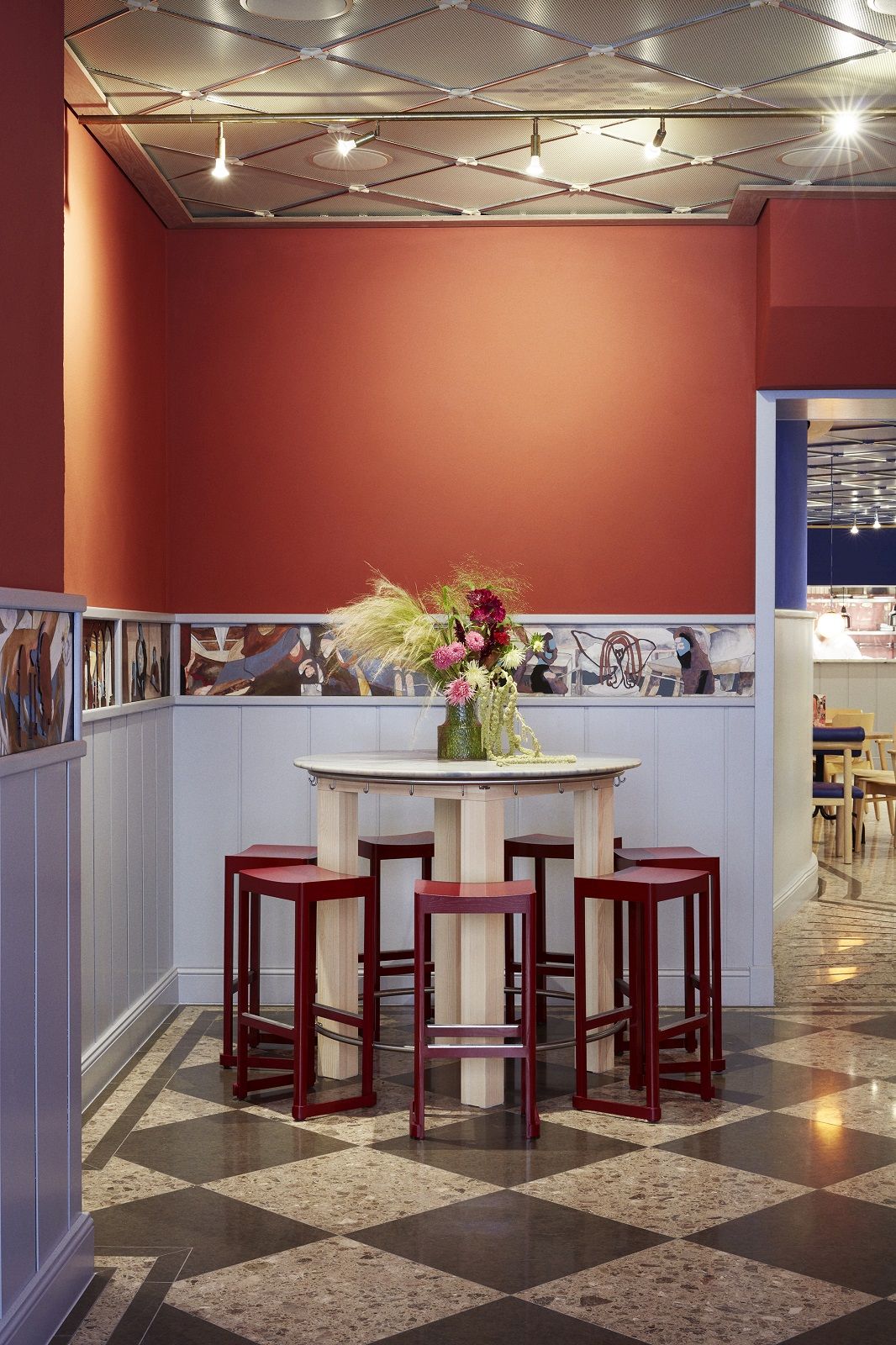 Roter Atelier Bar Stool Barhocker von Artek um einen runden Holztisch in einem Restaurant.