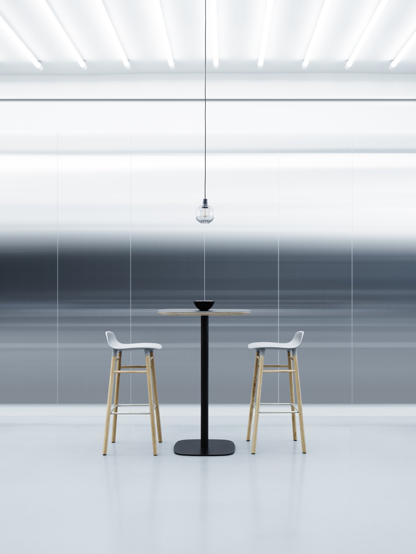 Zwei Form Barhocker H 75 cm von Normann Copenhagen an einem Stehtisch in minimalistischem Ambiente.