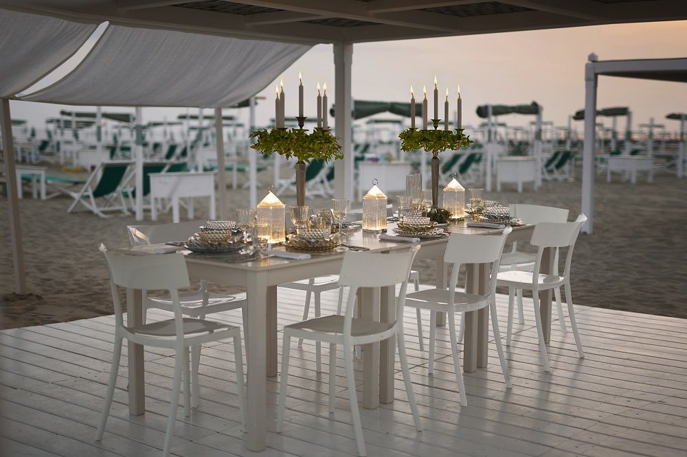 Catwalk Stuhl von Kartell, weiße Design Stühle an gedecktem Tisch am Strand mit Kerzenleuchtern.