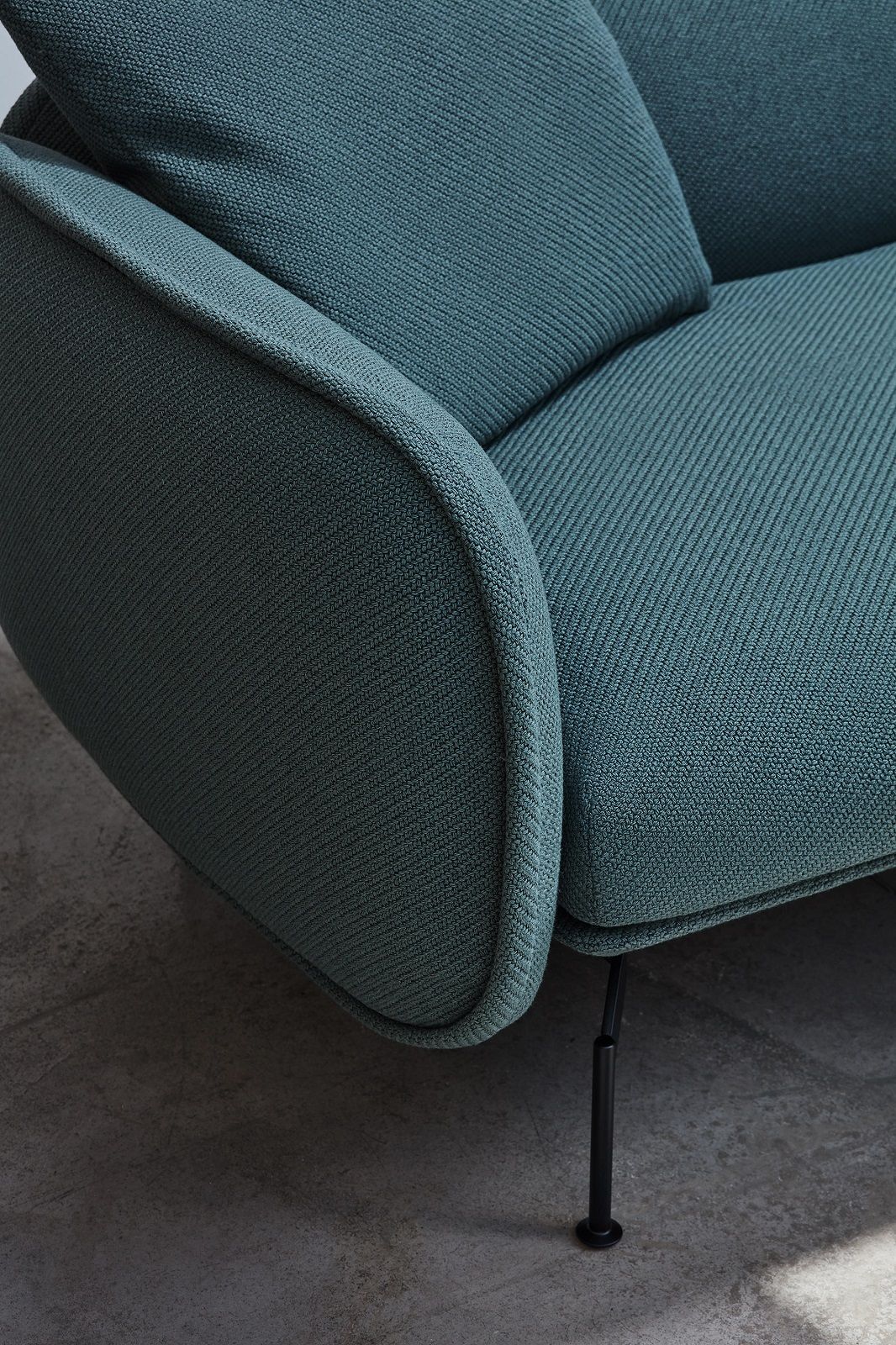 Detailaufnahme vom türkisfarbenen Prostoria Echo Sofa mit abgerundeter Armlehne und schwarzen Füßen.