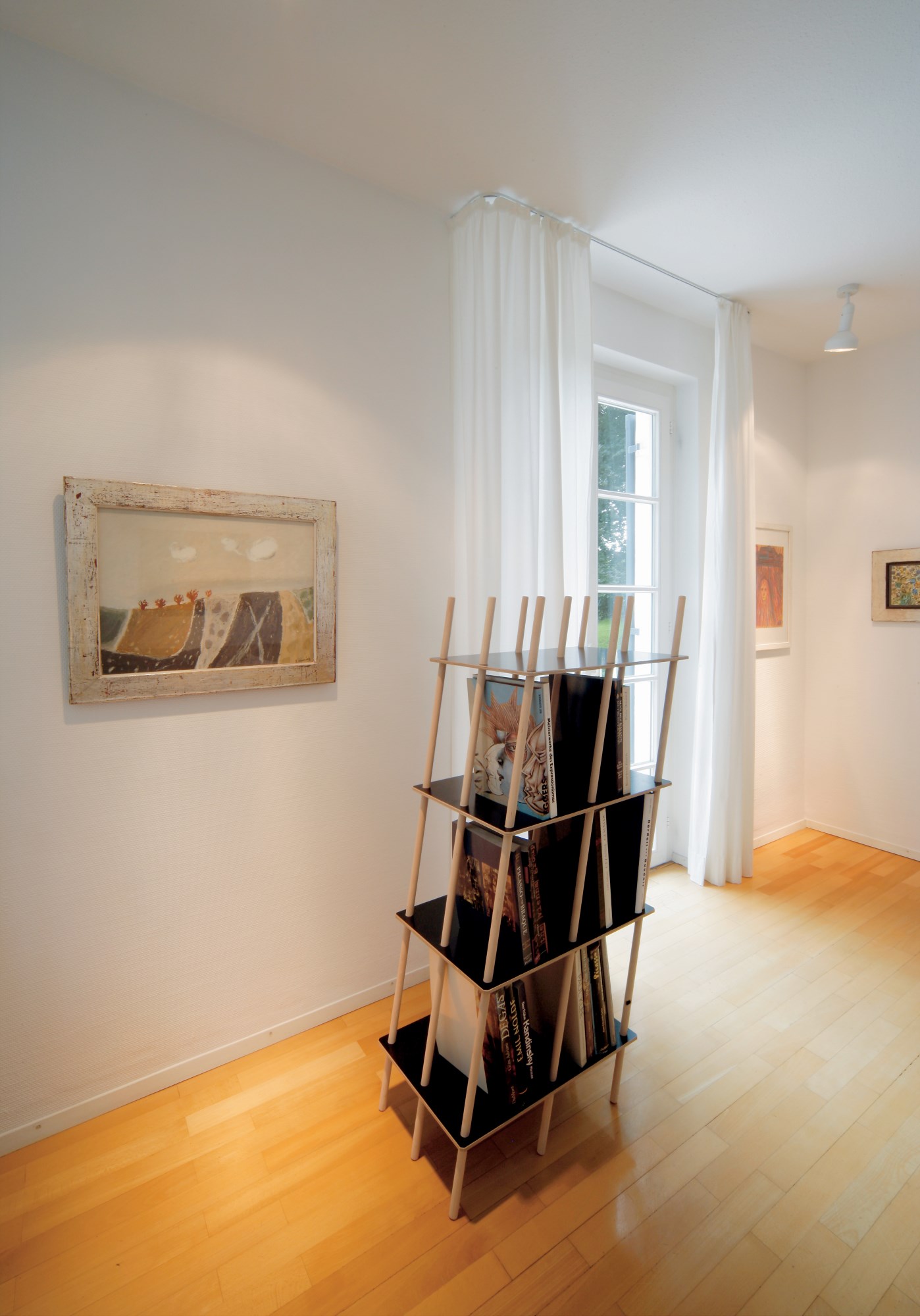 Nils Holger Moormann Regal "Es" aus Holz und schwarzem Regalbrettern im minimalistischen Wohnzimmer.