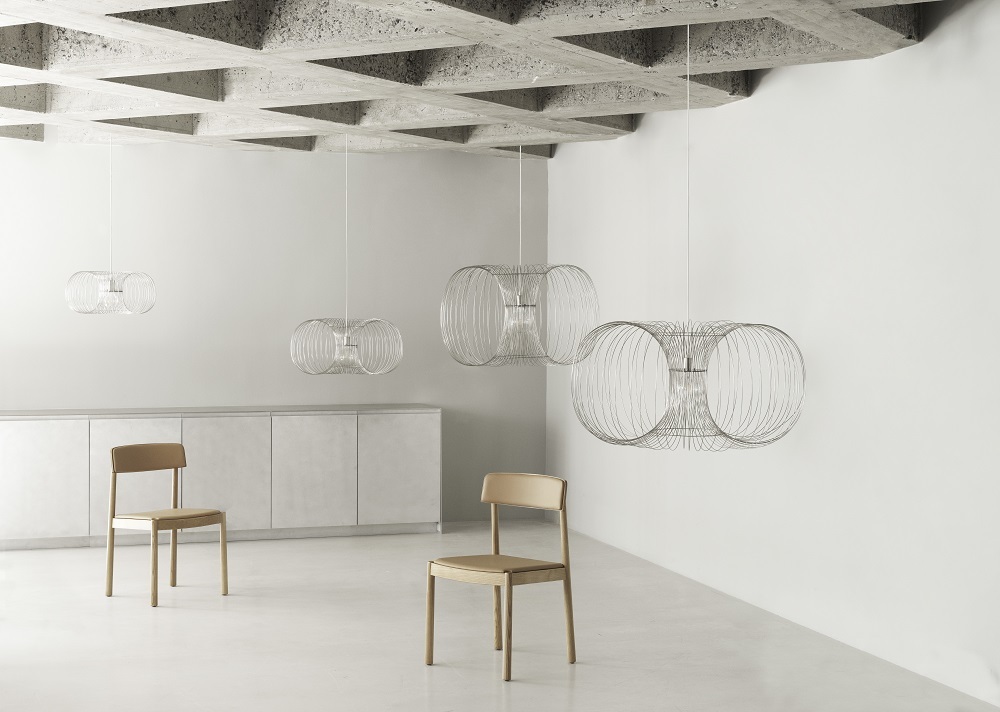 Coil Lampe von Normann Copenhagen: Draht-Pendelleuchte in modernem Wohnraum mit Stühlen.