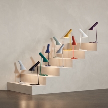 AJ Tischleuchten von Louis Poulsen in verschiedenen Farben auf einer Treppe, modernes Design.
