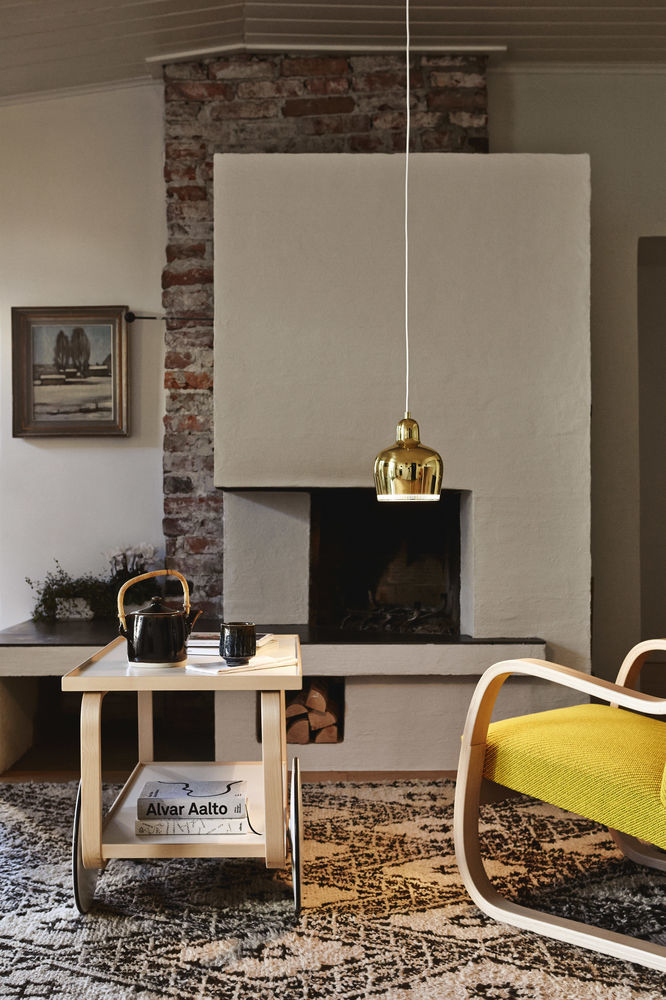 Goldene A330S Golden Bell Pendelleuchte von Artek über einem Wohnzimmer mit Kamin und Teewagen.