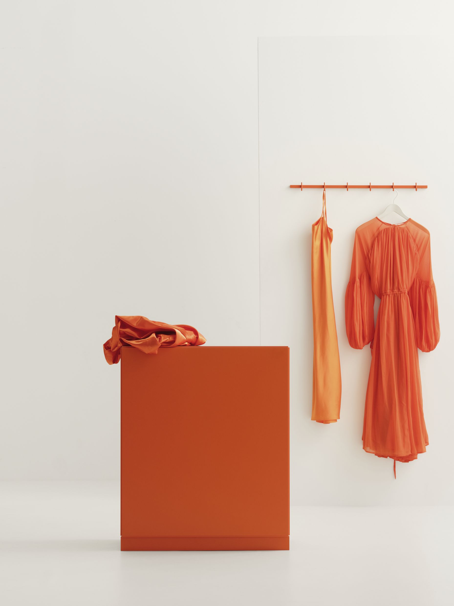 Graue Relief Hakenleiste B82cm von String Furniture an einer Wand mit Kleidung.