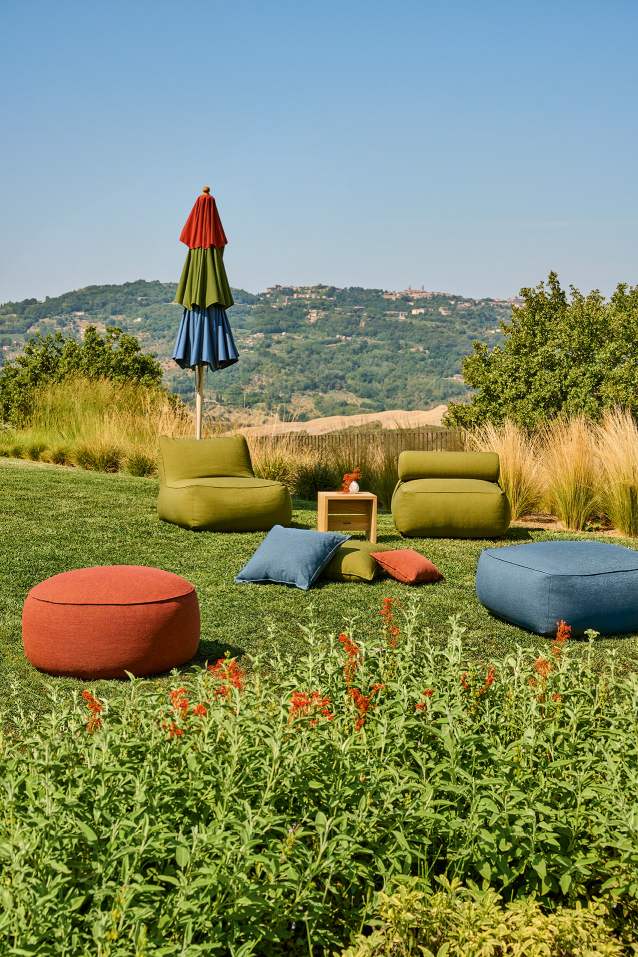 Weishäupl Sonnenschirm und Gartenmöbel-Set auf Rasen mit Blick auf grüne Hügellandschaft an einem sonnigen Tag.