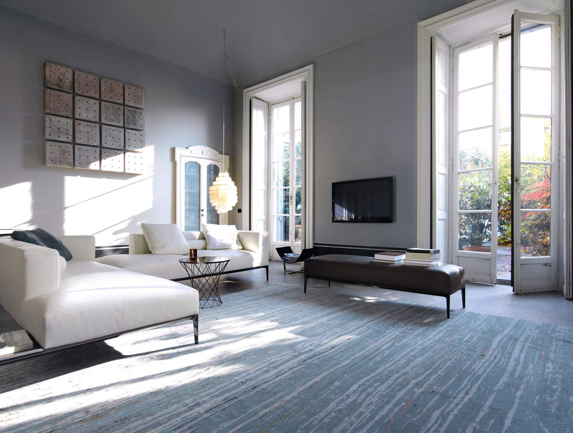 Helles Wohnzimmer mit weißer Jaan Living Polsterbank und brauner Lederbank von Walter Knoll.