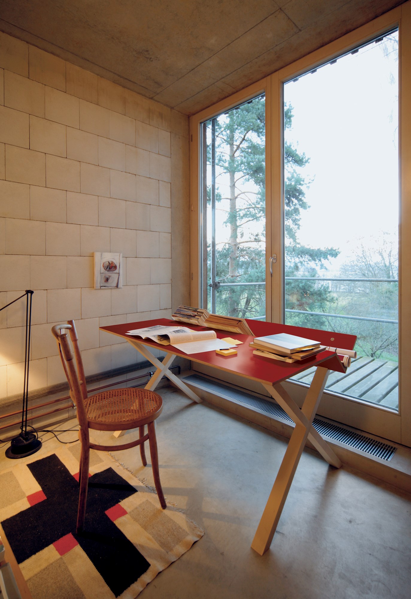 Roter Kant Schreibtisch von Nils Holger Moormann in minimalistischem Raum mit Stuhl und Teppich.