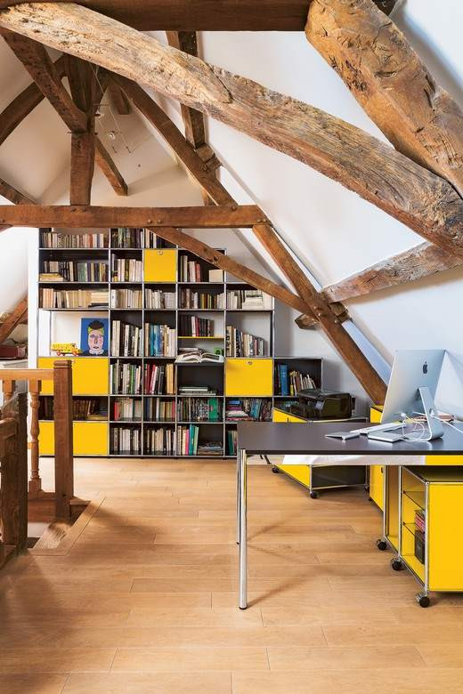 Heller Büroeinrichtung im Dachgeschoss mit USM Haller Tisch, Regal in Weiß und Gelb.
