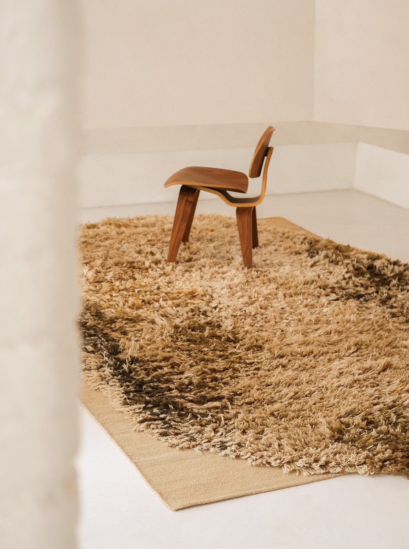 Nanimarquina Alga Rug Teppich in Beige-Braun mit Holzstuhl auf hellem Untergrund. Hochfloriger Teppich.