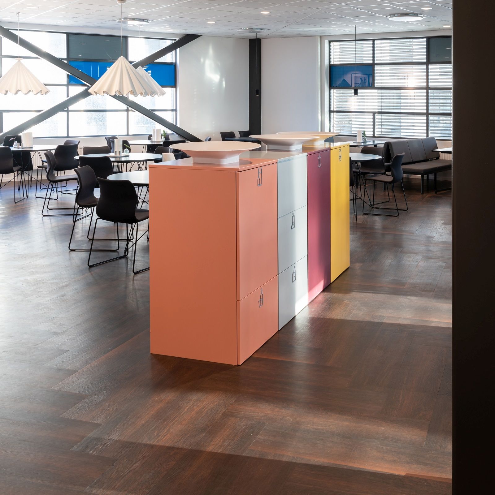Farbenfrohe Exhibit Bin Mülleimer zur Mülltrennung von Mizetto in modernem Büro mit Tischen und Stühlen.