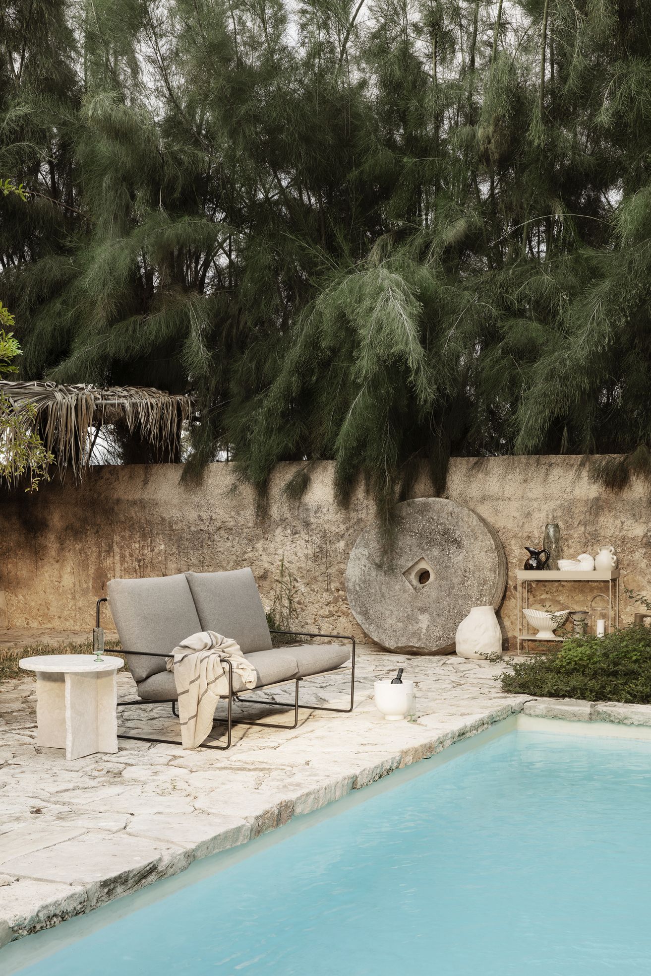 Desert 2-Sitzer Sofa von Ferm Living mit schwarzem Gestell neben einem Pool im Freien.