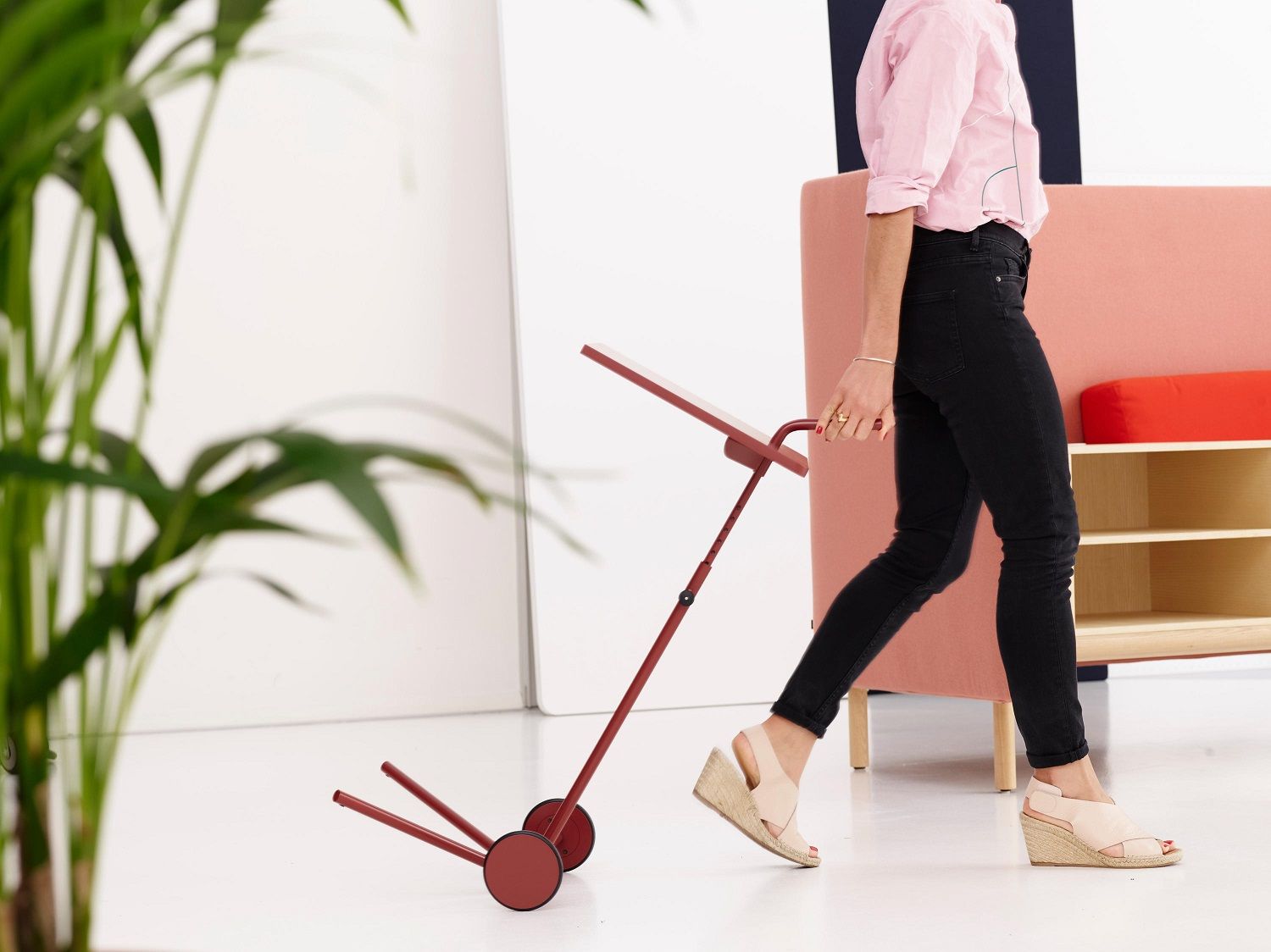 Frau schiebt roten Bond Laptoptisch mit Rollen, höhenverstellbar, für flexibles Arbeiten im Homeoffice.