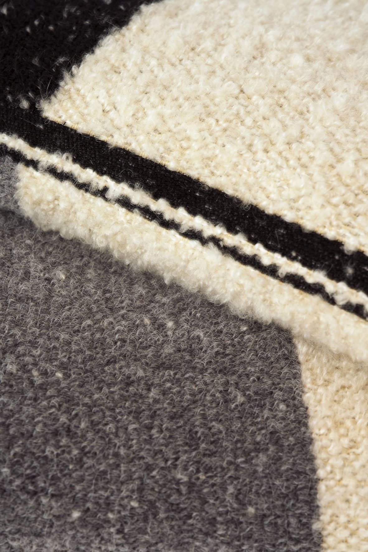 Detailaufnahme des Urban Überwurfs von Ethnicraft: Weiche Wolle mit abstraktem, grafischem Muster in Schwarz, Grau und Creme.