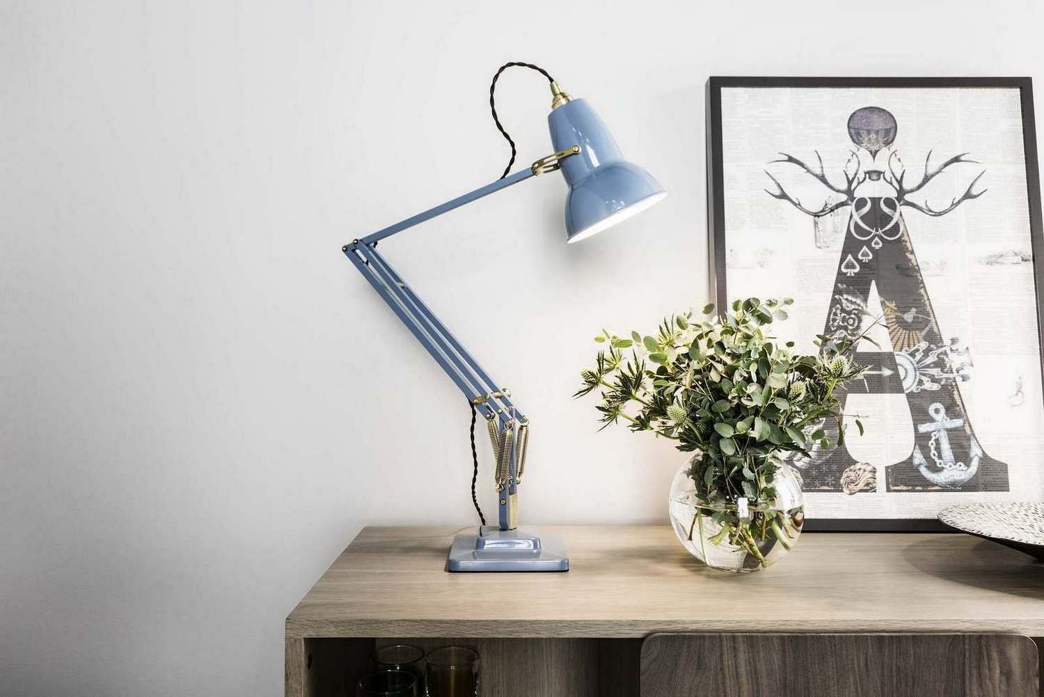 Original 1227 Anglepoise Tischleuchte aus Messing in Taubengrau auf einem Holztisch mit Dekoration.