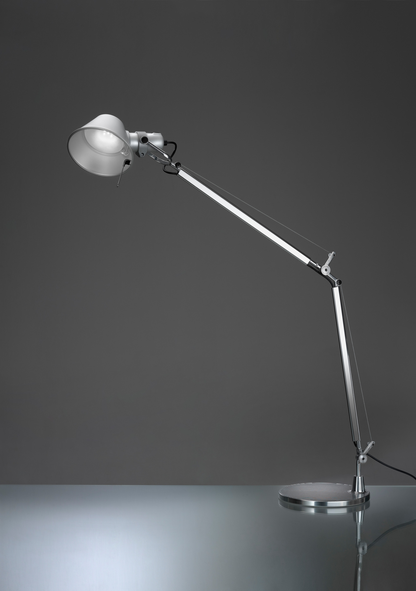 Silberne Tolomeo LED Tischleuchte von Artemide mit verstellbarem Arm und Lampenschirm auf Tisch.