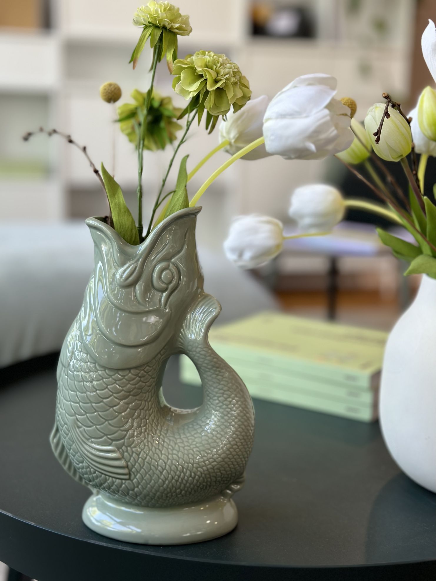 Grüne Fischvase aus Keramik mit Blumenarrangement, dekorative Wohnaccessoires für Tischdekoration und modernes Interieur.