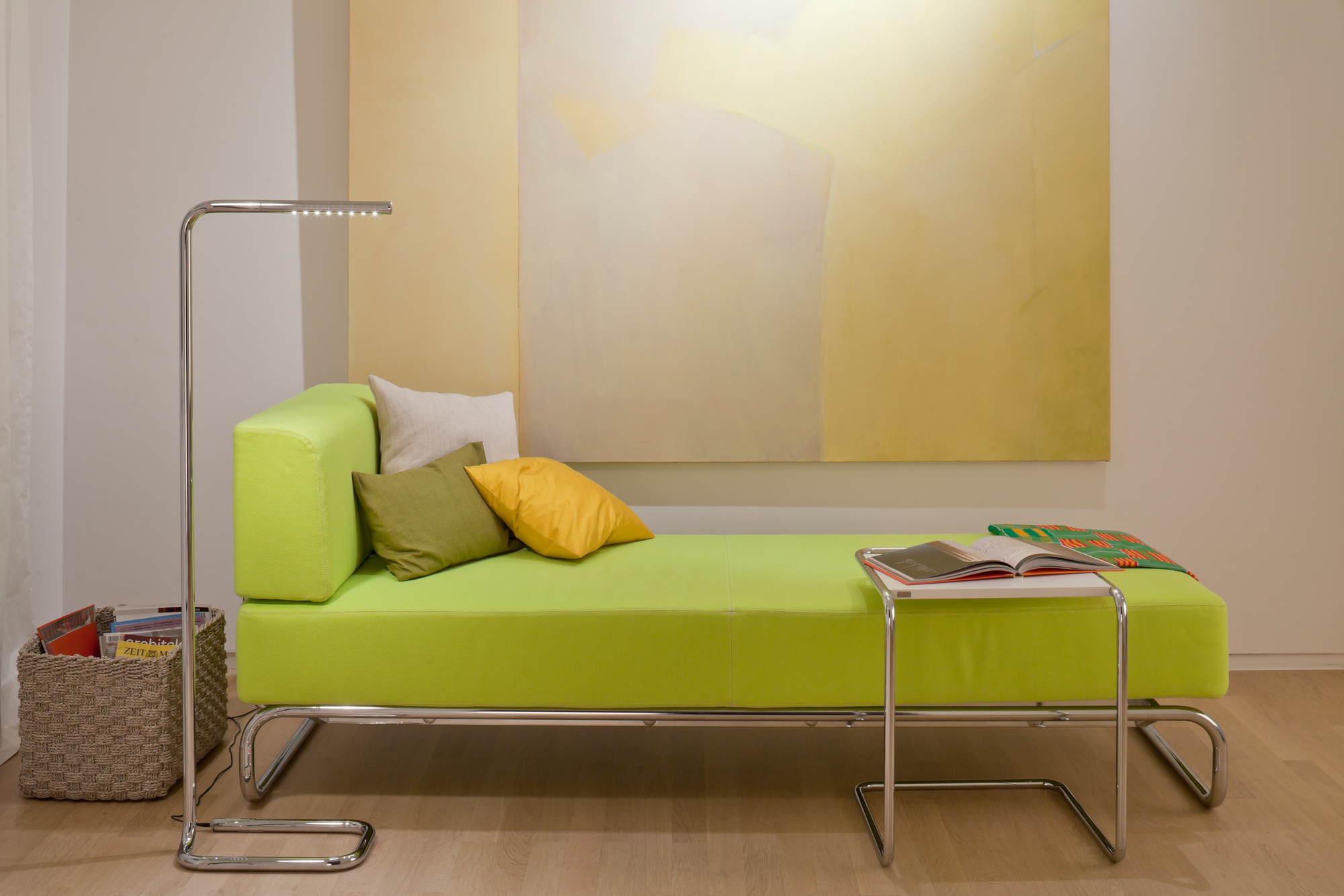 B97 Thonet Beistelltisch mit Stahlrohrgestell neben grüner Ottomane und Stehlampe im modernen Wohnzimmer.