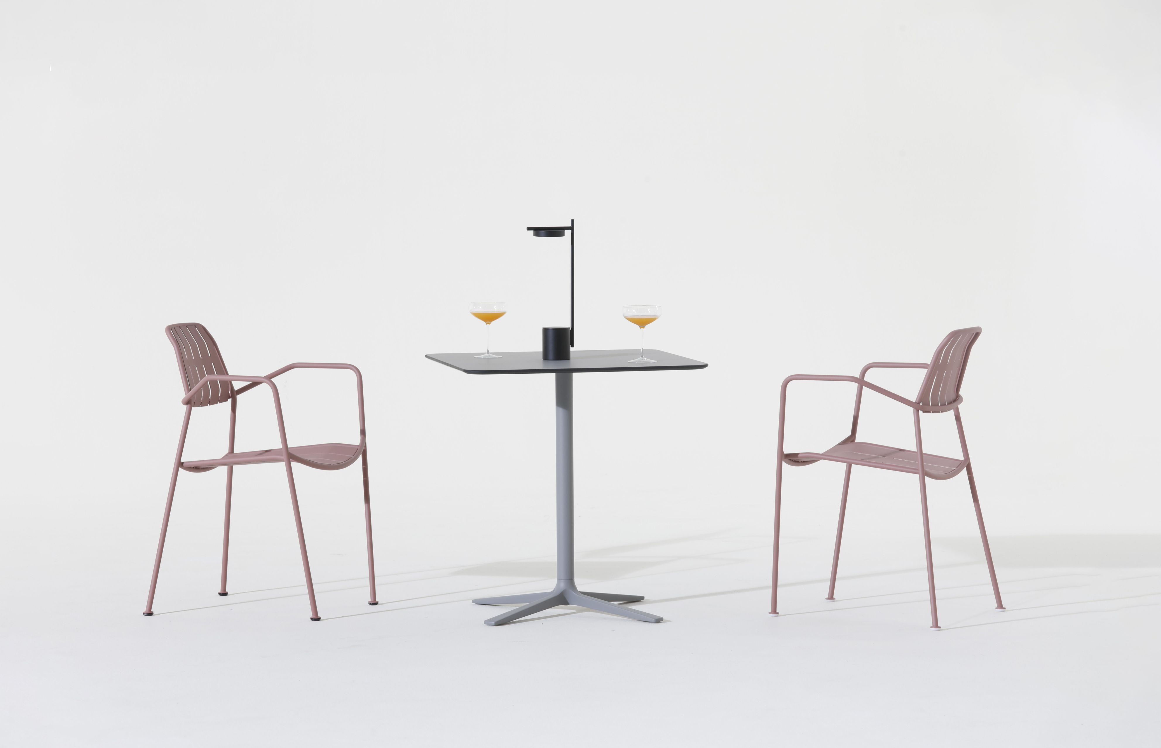 Osmo Outdoor Stuhl Teak Prostoria, rosafarbene Gartenstühle mit Armlehne und Tisch mit Getränken auf weißem Hintergrund.