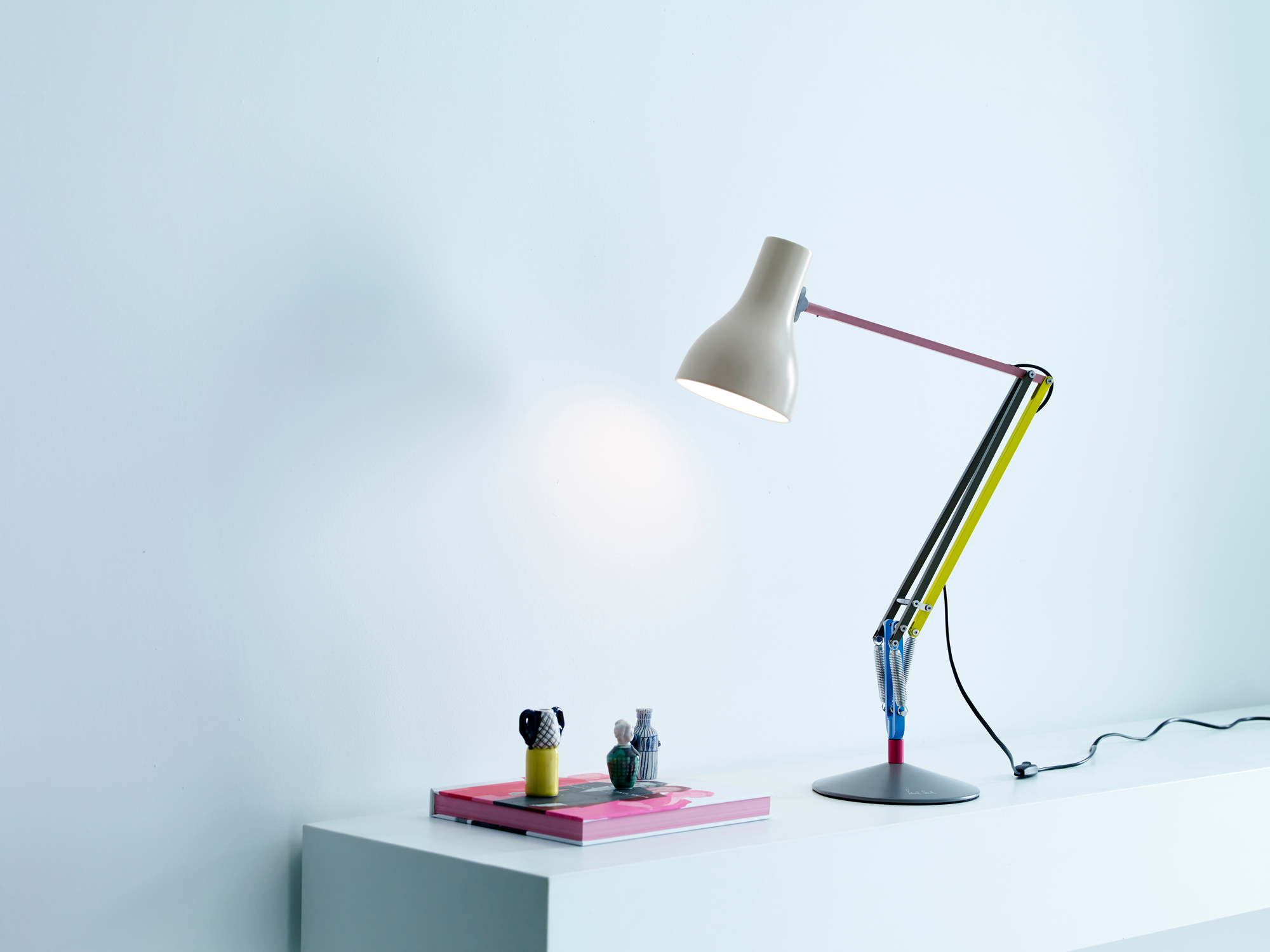Anglepoise Type 75 Mini Paul Smith Edition 1 Tischleuchte in Beige mit farbigen Akzenten auf weißem Tisch.