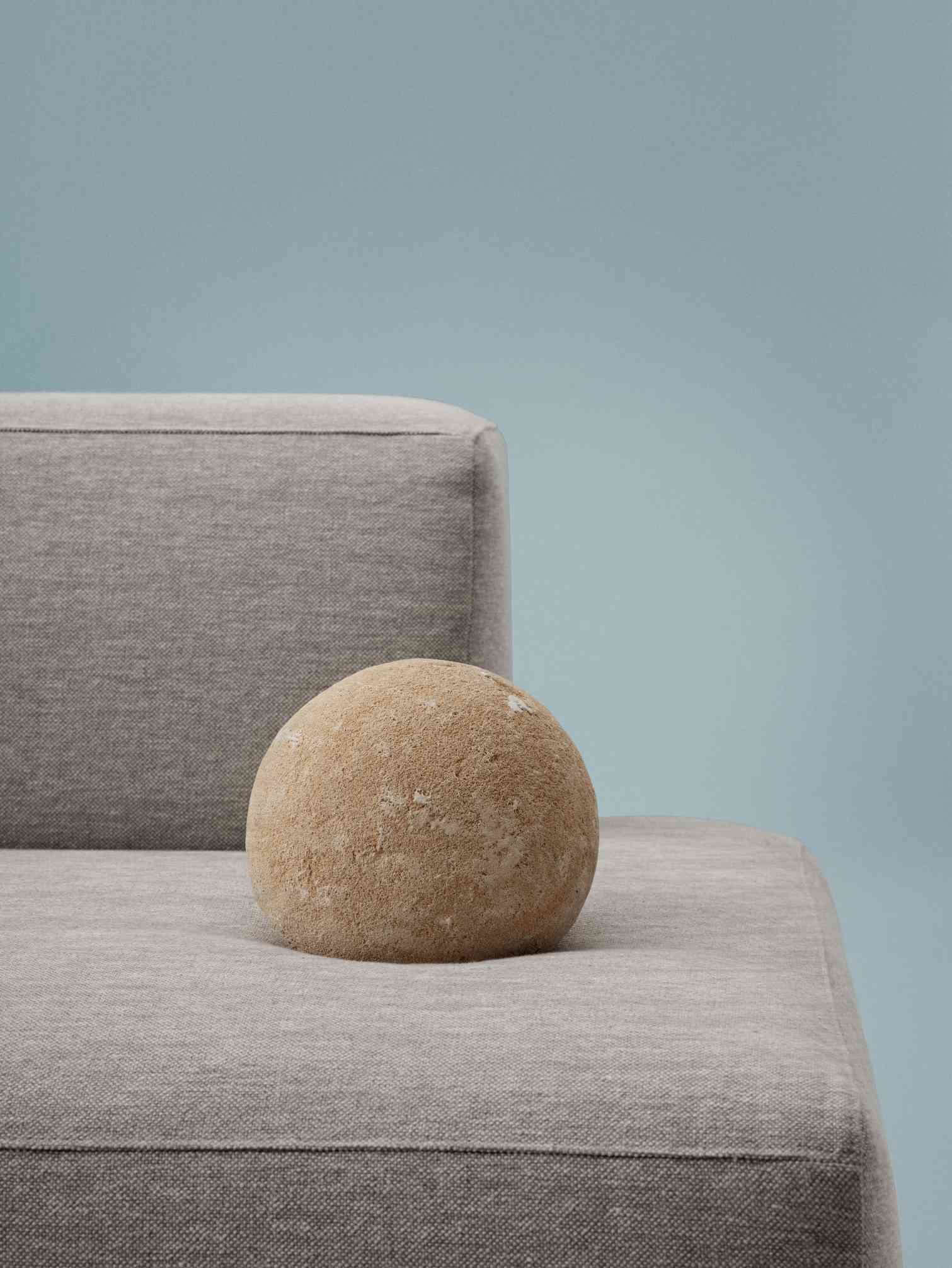 Detailaufnahme des grauen Connect Soft Sofas von Muuto mit dekorativem Steinobjekt. Gemütliches modulares Sofa.