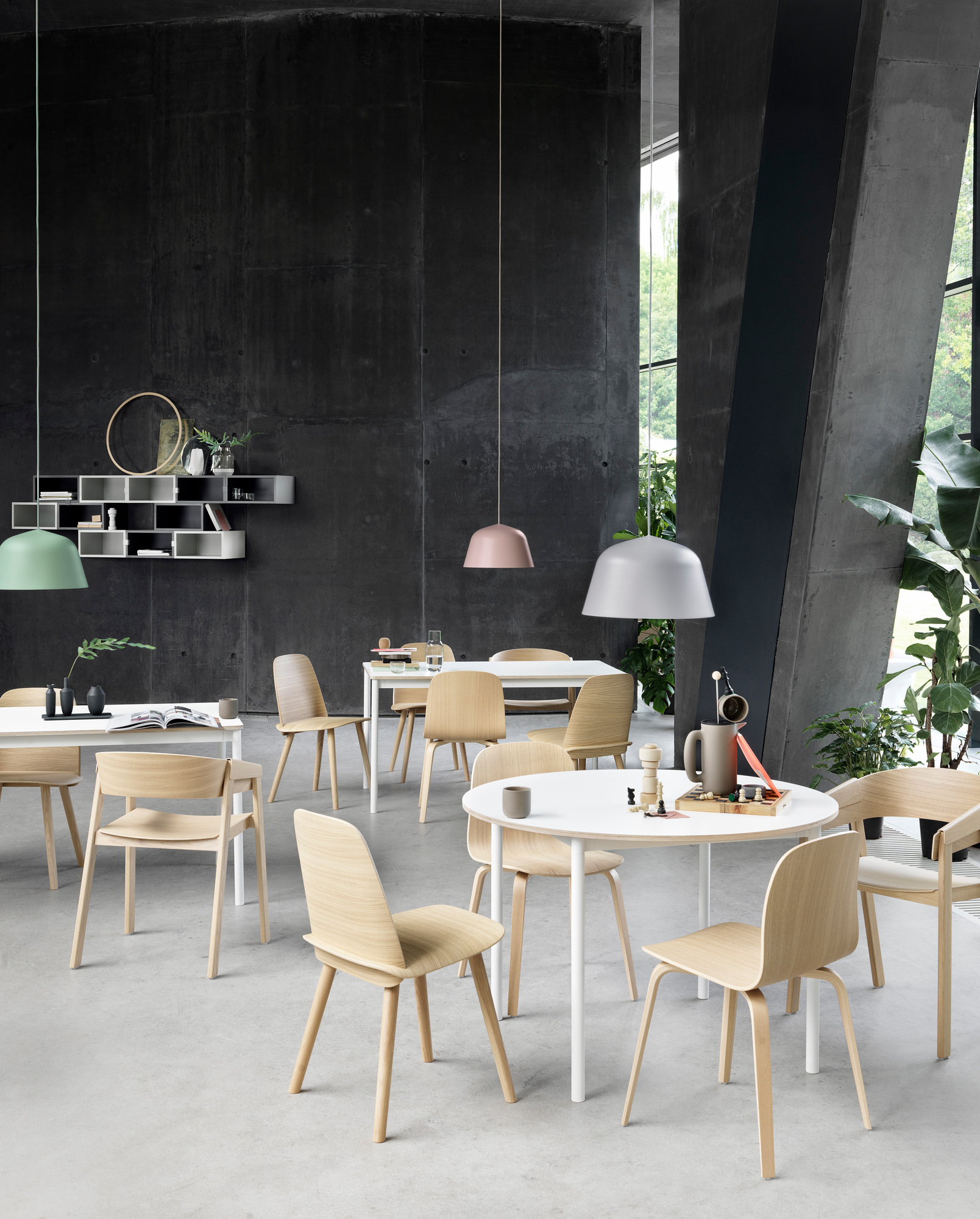 Helle Holztöne des Muuto Nerd Chair Stuhls in modernem Ambiente mit Tischen und Pendelleuchten.