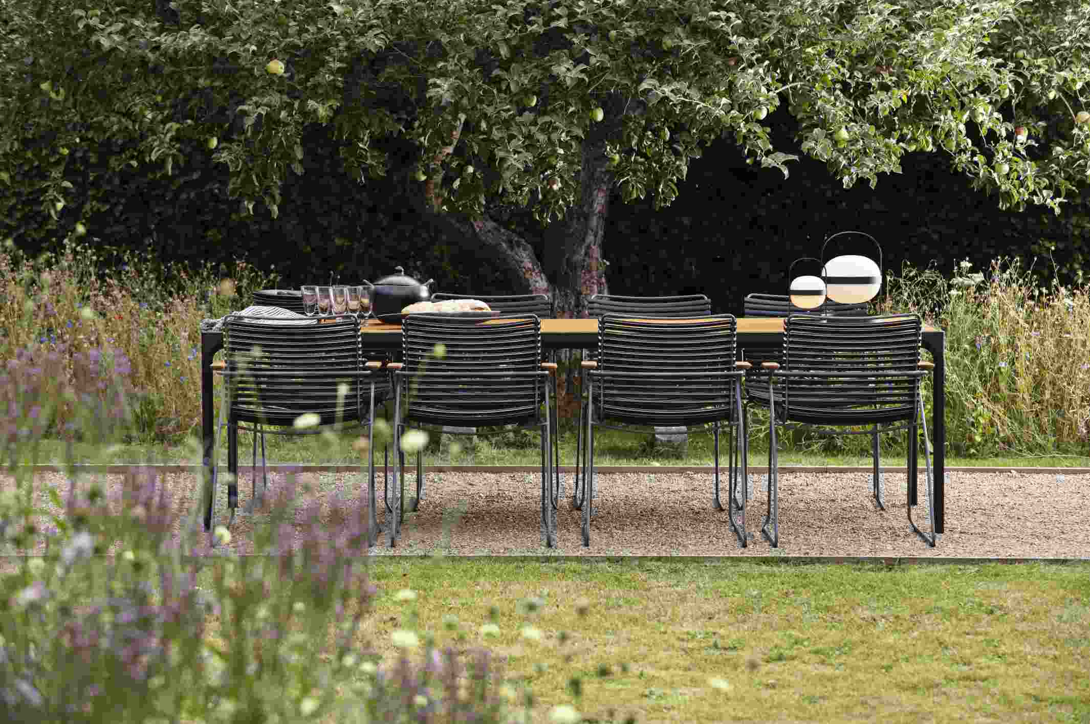 Schwarzer Click Dining Stuhl mit Armlehne von Houe am Gartentisch im Freien. Outdoor Möbel.
