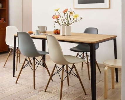 Esstisch aus Holz mit schwarzen Beinen und bunten Kunststoffstühlen im modernen Esszimmer.