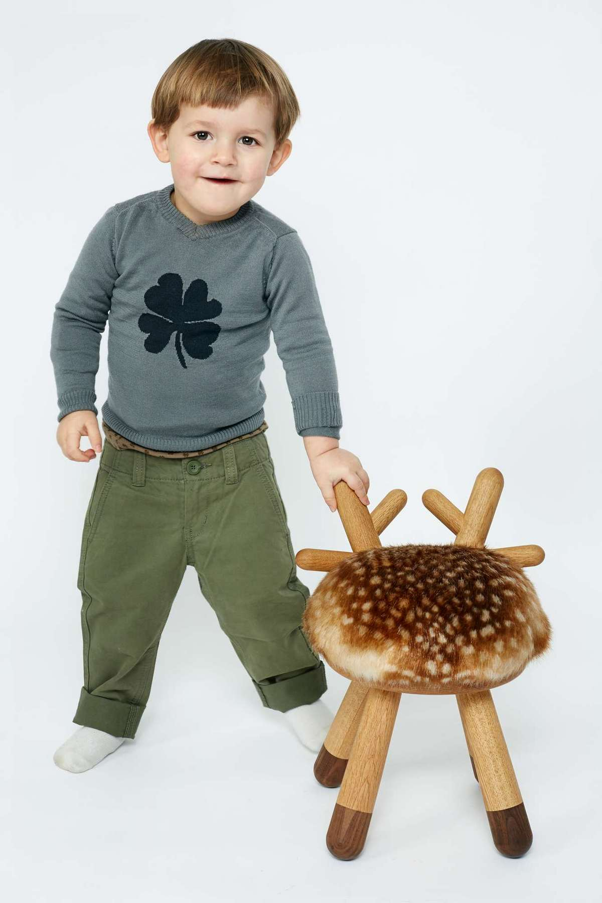 Kleiner Junge steht neben Bambi Chair Kinderstuhl mit Fellimitat und Holzbeinen.