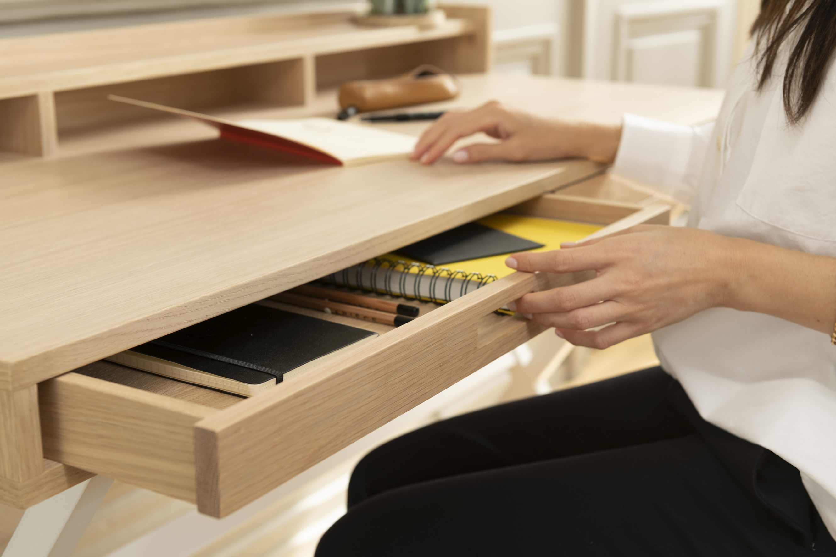 Hyppolite Sekretär aus hellem Holz mit offener Schublade, gefüllt mit Notizbüchern und Stiften.