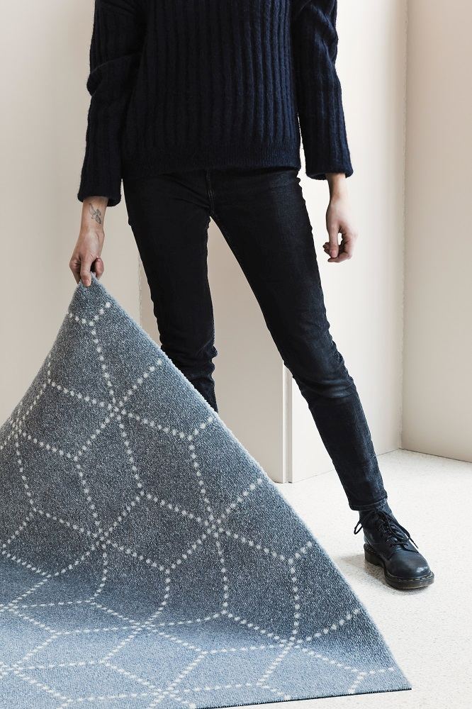 Person hält blaue Hagl Heymat Fußmatte mit geometrischem Muster für Innen und Außen.