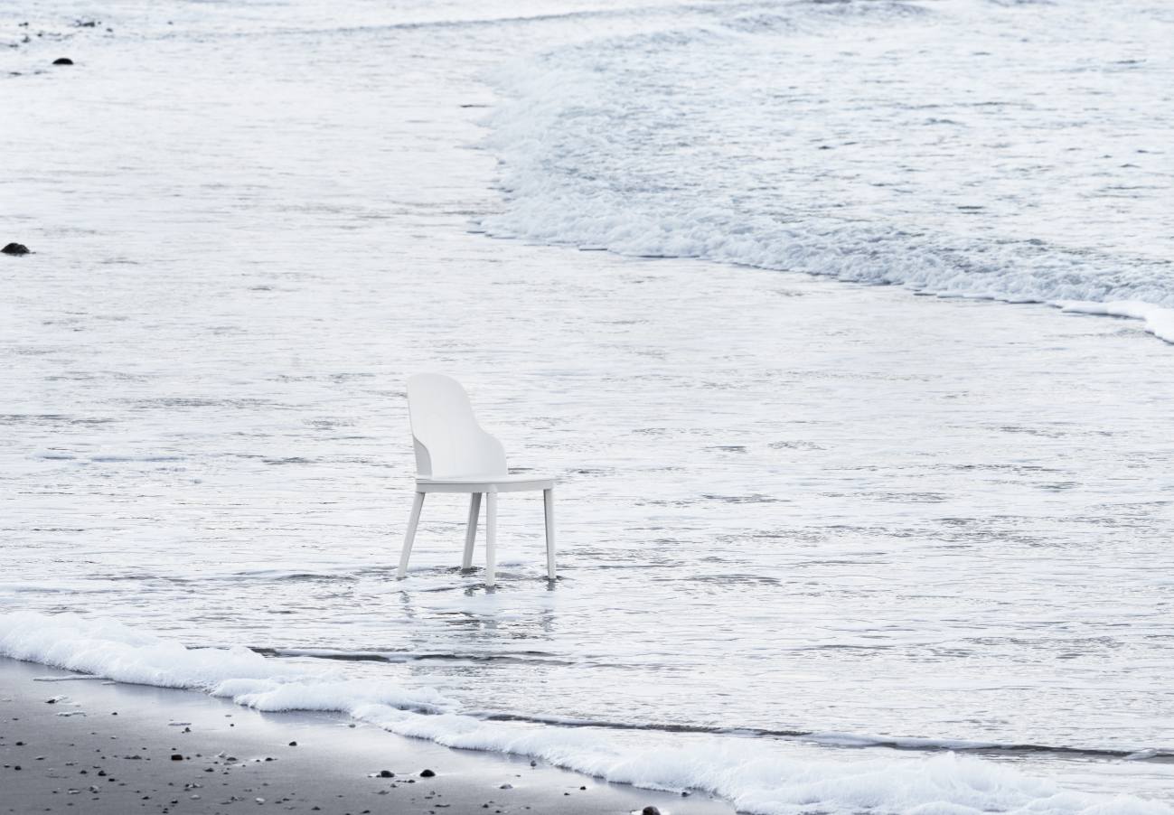 Weißer Allez Chair PP Stuhl von Normann Copenhagen steht im flachen Wasser am Strand.