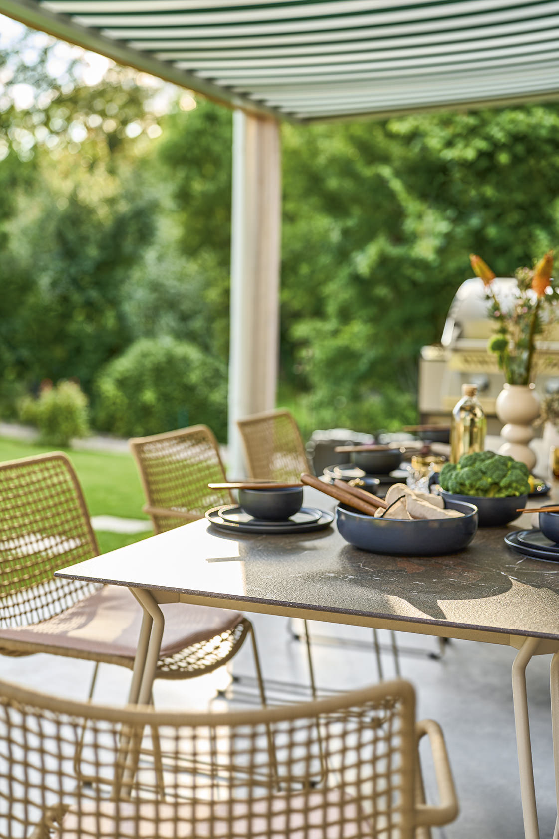 Weishäupl Slope Tisch, ein moderner Outdoor Esstisch mit Geschirr und Stühlen im Garten.